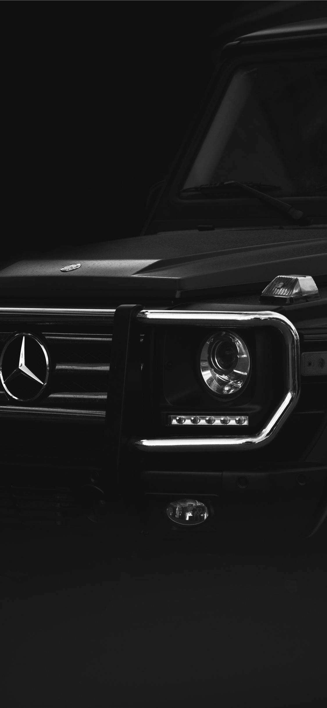 Mercedes 桌布 壁紙 — 時尚黑色 Mercedes G-Wagen 前格柵和頭燈在戲劇性的攝影棚燈光下，在漆黑的背景中閃耀。