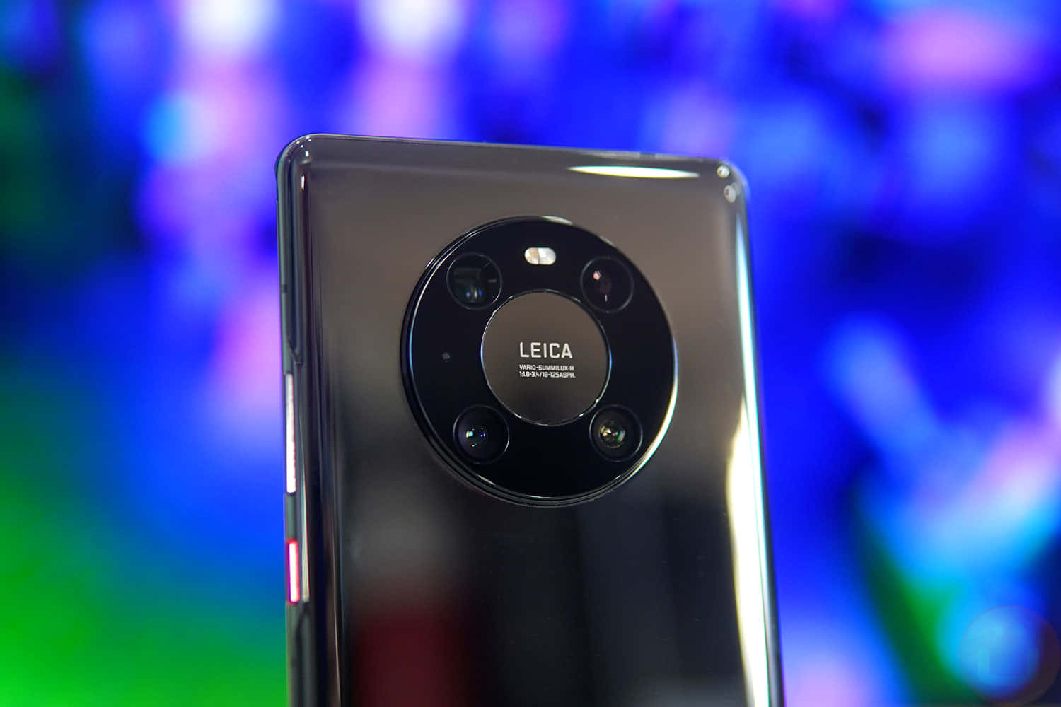 黑色智慧型手機帶有 Leica 相機模組，背景為彩色模糊效果。