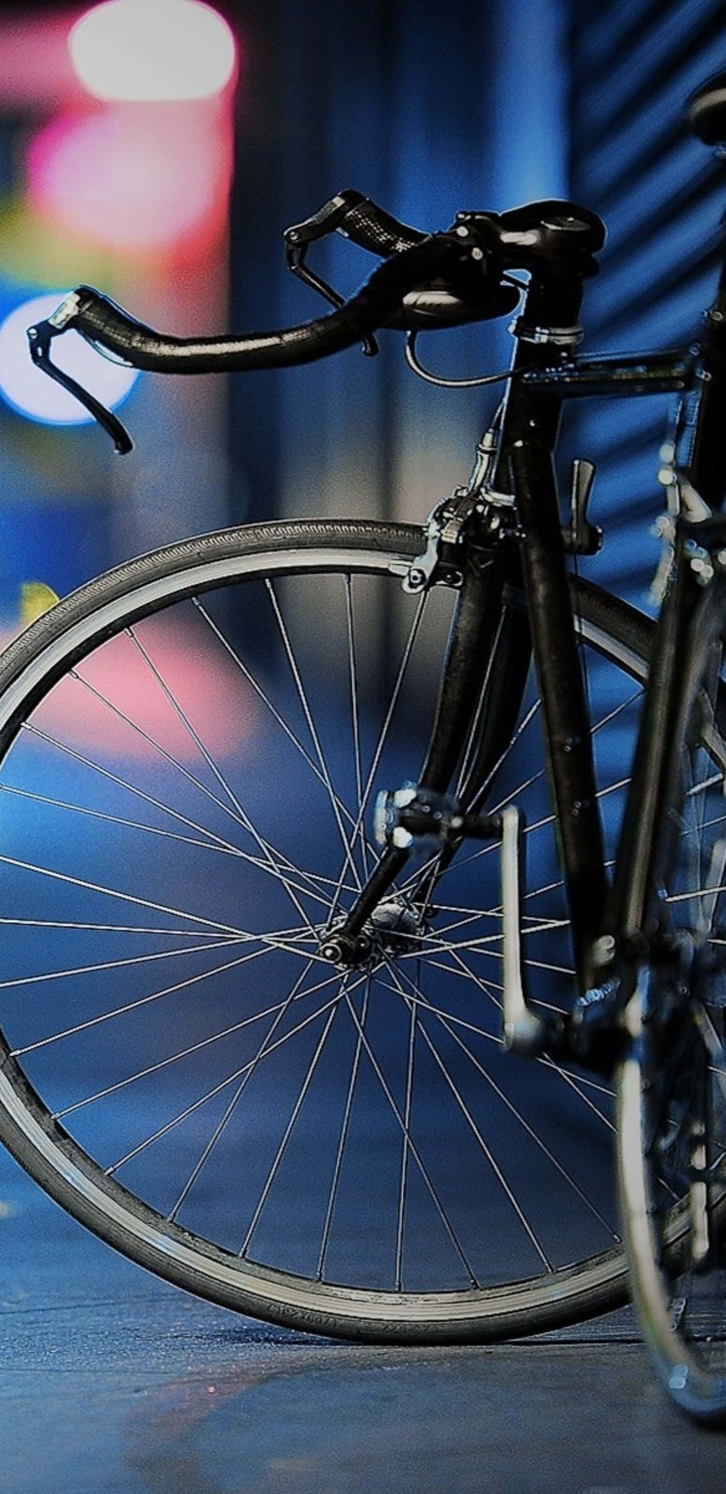 Pixel 3xl Bikes 桌布 壁紙 — 時尚黑色自行車輪和把手在模糊的霓虹燈城市夜景背景下的特寫。