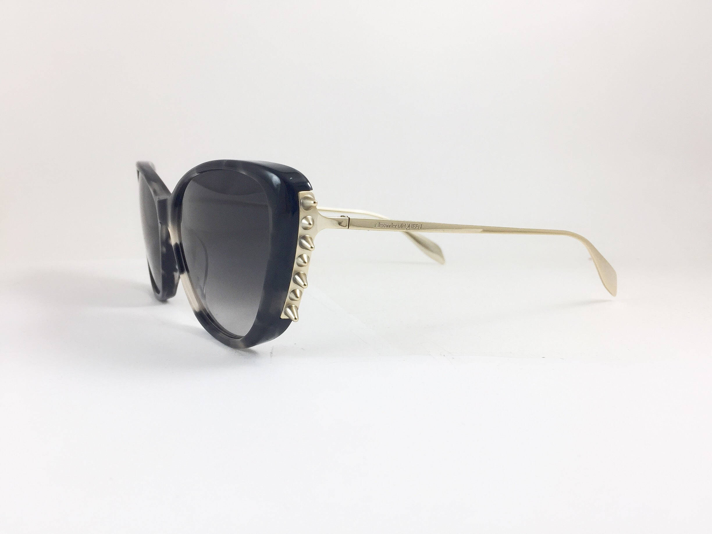Sunglasses 桌布 壁紙 — 時尚黑色貓眼太陽眼鏡，金色鉚釘鏡腿，置於純白表面上。