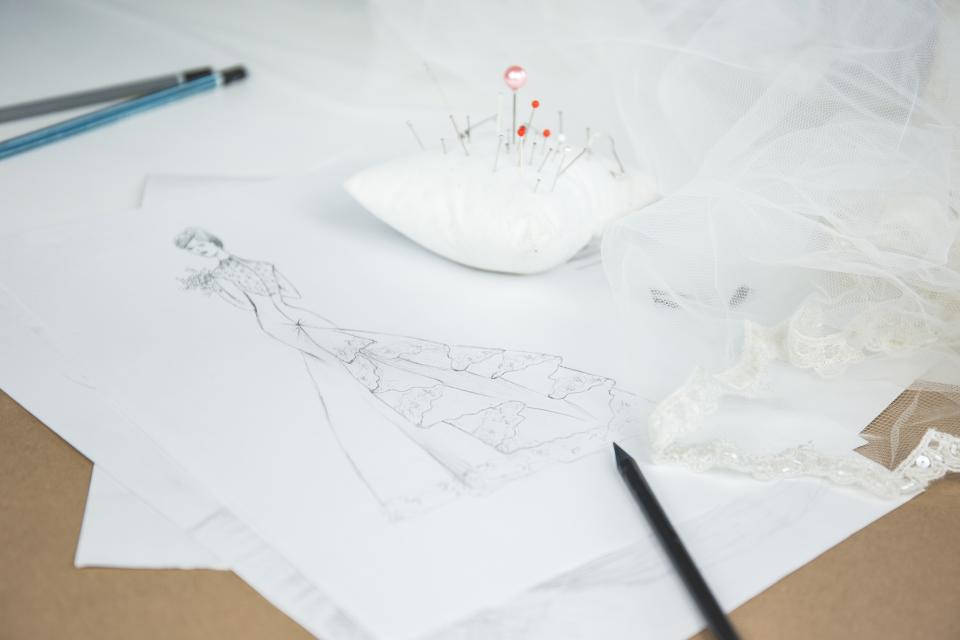 pencil 桌布 壁紙 — 時裝設計師的工作空間，木桌上放有婚紗草圖、用別針固定的布料、鉛筆和蕾絲。