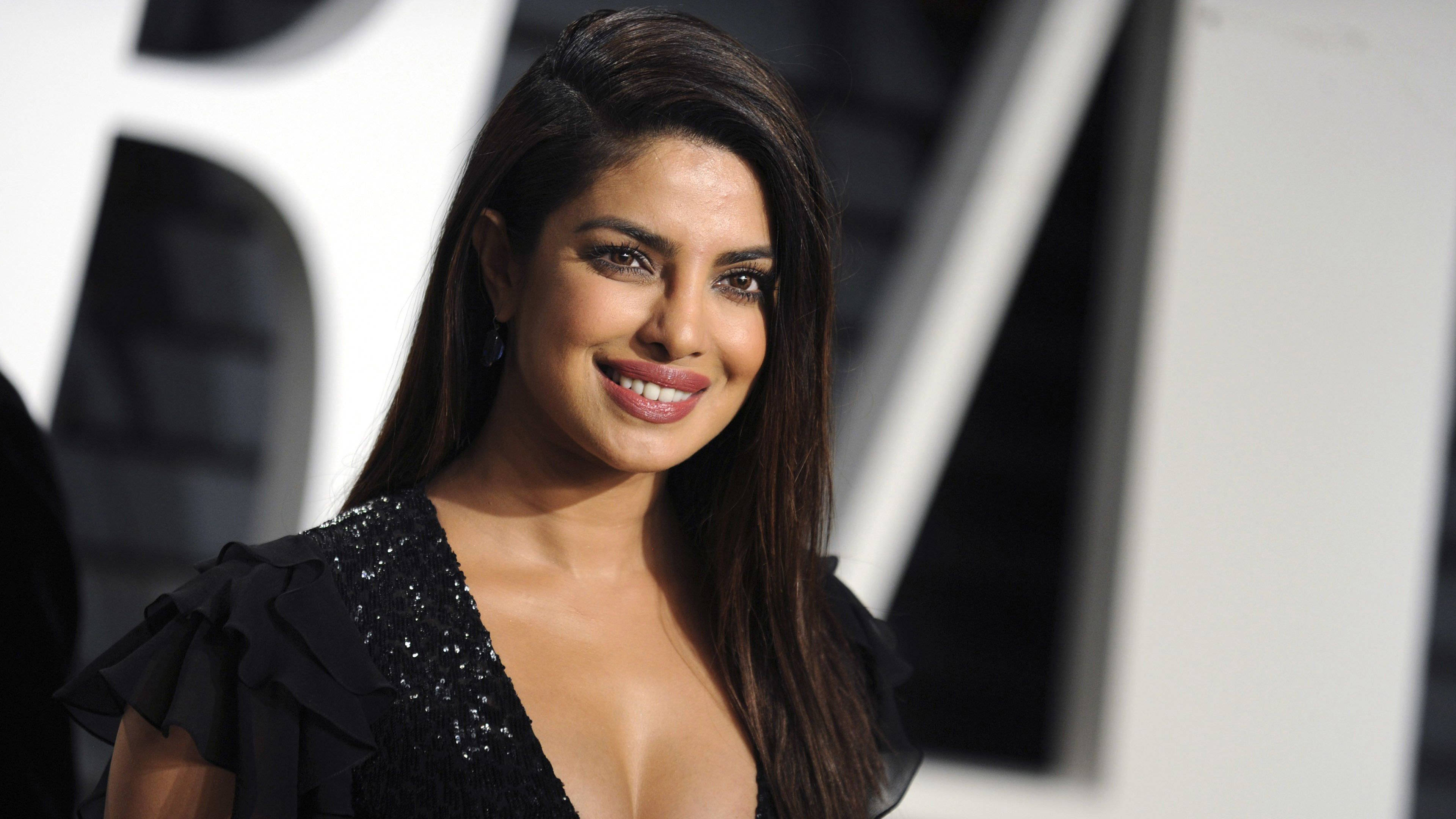 Priyanka 桌布 壁紙 — 普里揚卡·喬普拉身穿黑色亮片連衣裙，在黑白幾何背景前溫暖微笑。