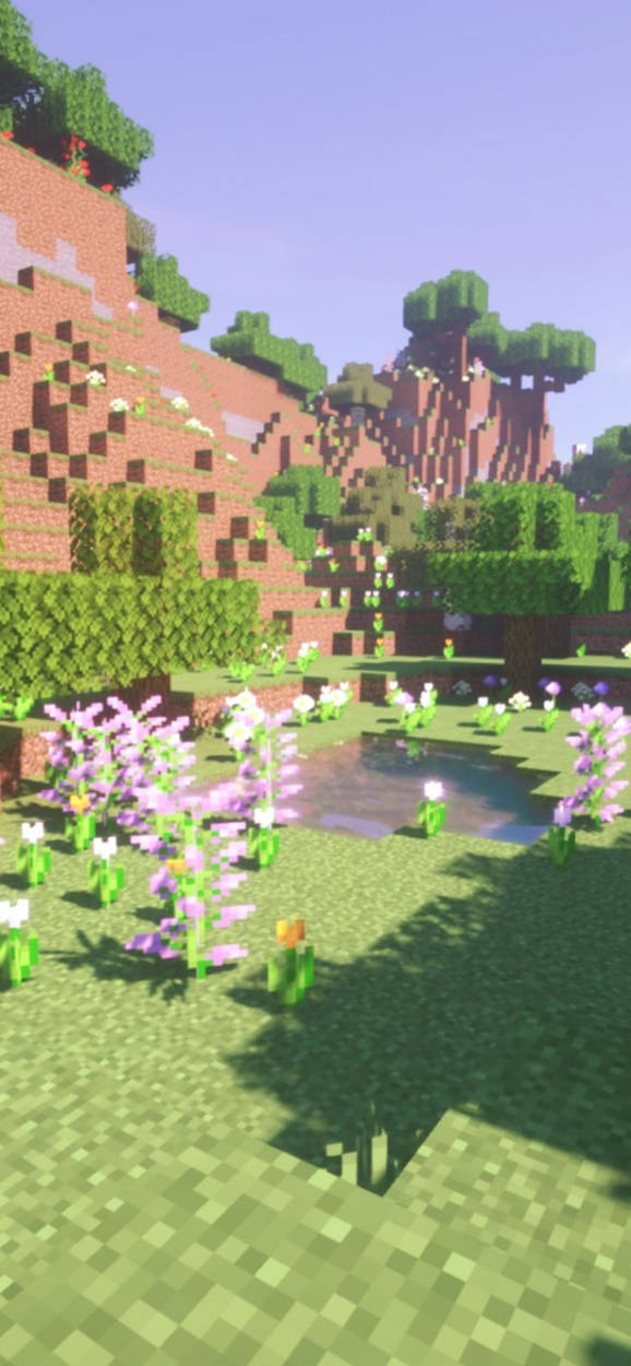 Animated 桌布 壁紙 — 晴朗天空下，一個像素化的Minecraft風景，周圍有草花和樹木環繞著一個小池塘。