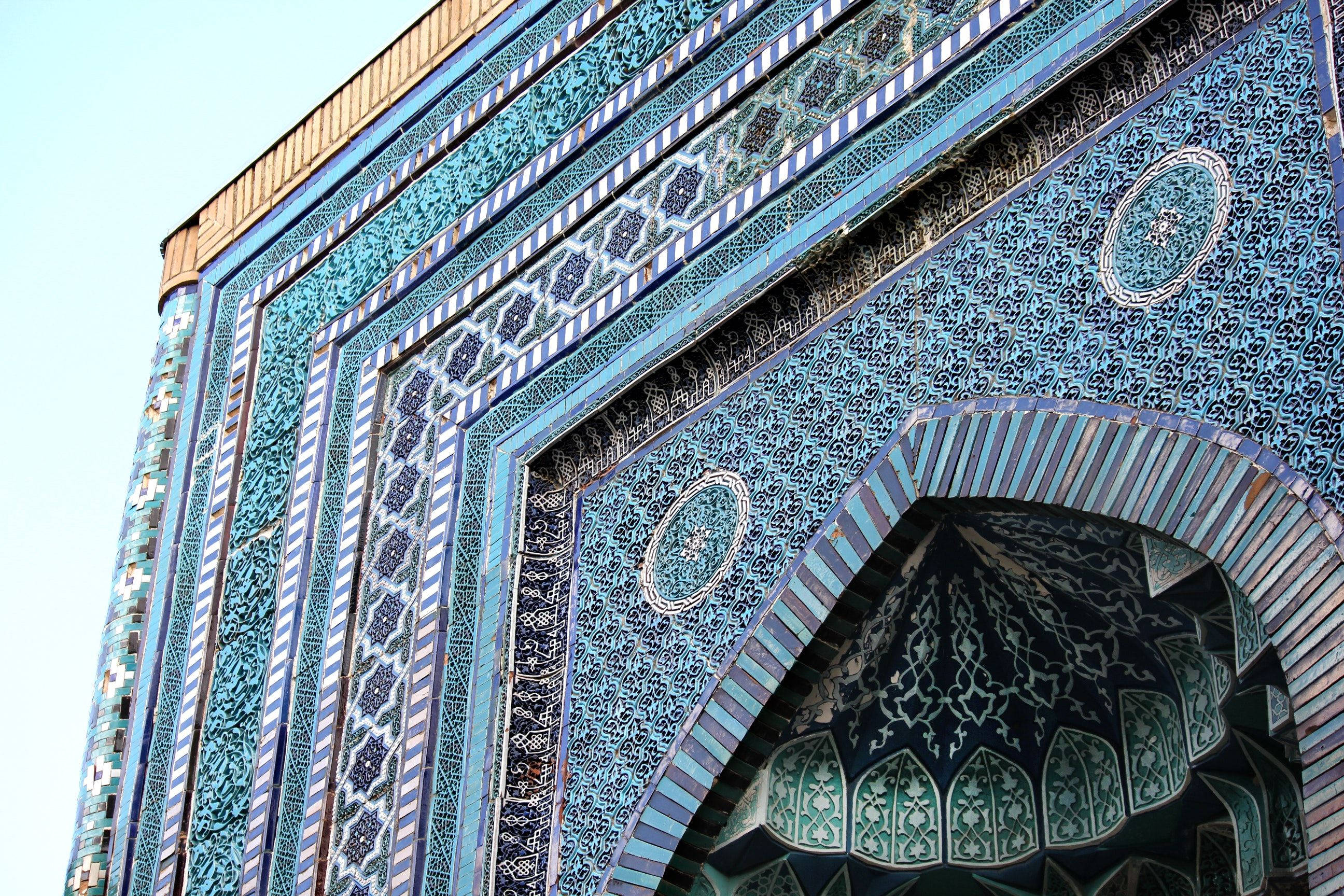 Uzbekistan 桌布 壁紙 — 晴朗天空下，以精緻藍白瓷磚裝飾的華麗伊斯蘭拱門的低角度視圖。
