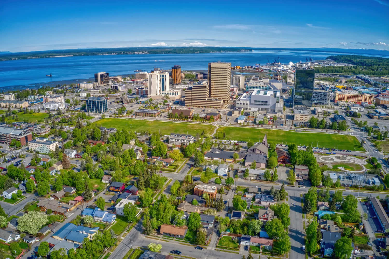 Neighborhood 桌布 壁紙 — 晴朗天空下，俯瞰一座充滿活力的城市景觀，毗鄰廣闊的藍色水域。