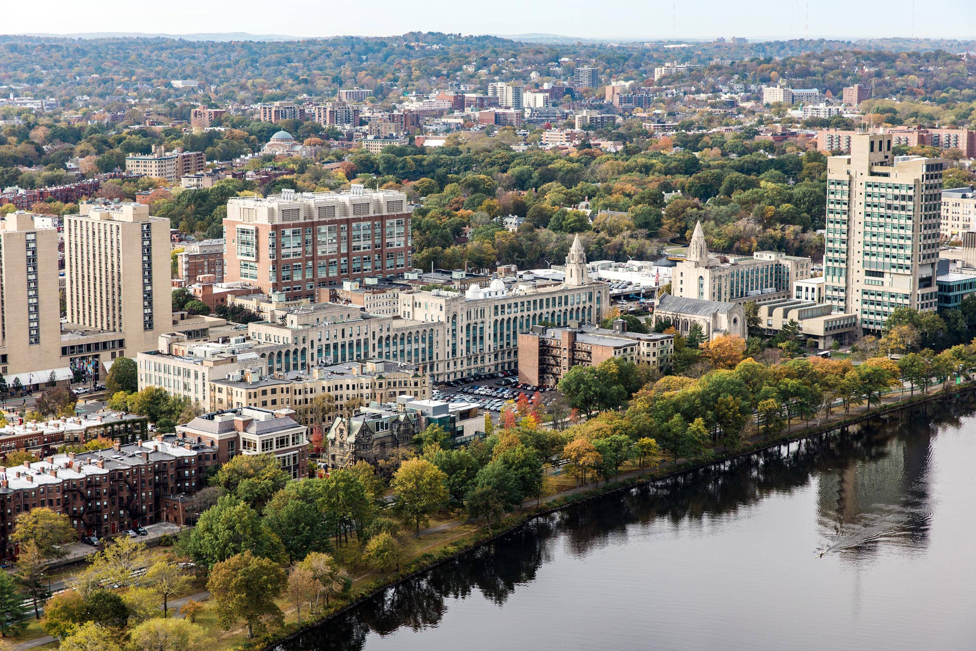 Boston 桌布 壁紙 — 晴朗天空下，河邊排列著秋樹，倒映建築物的城市景觀鳥瞰圖。