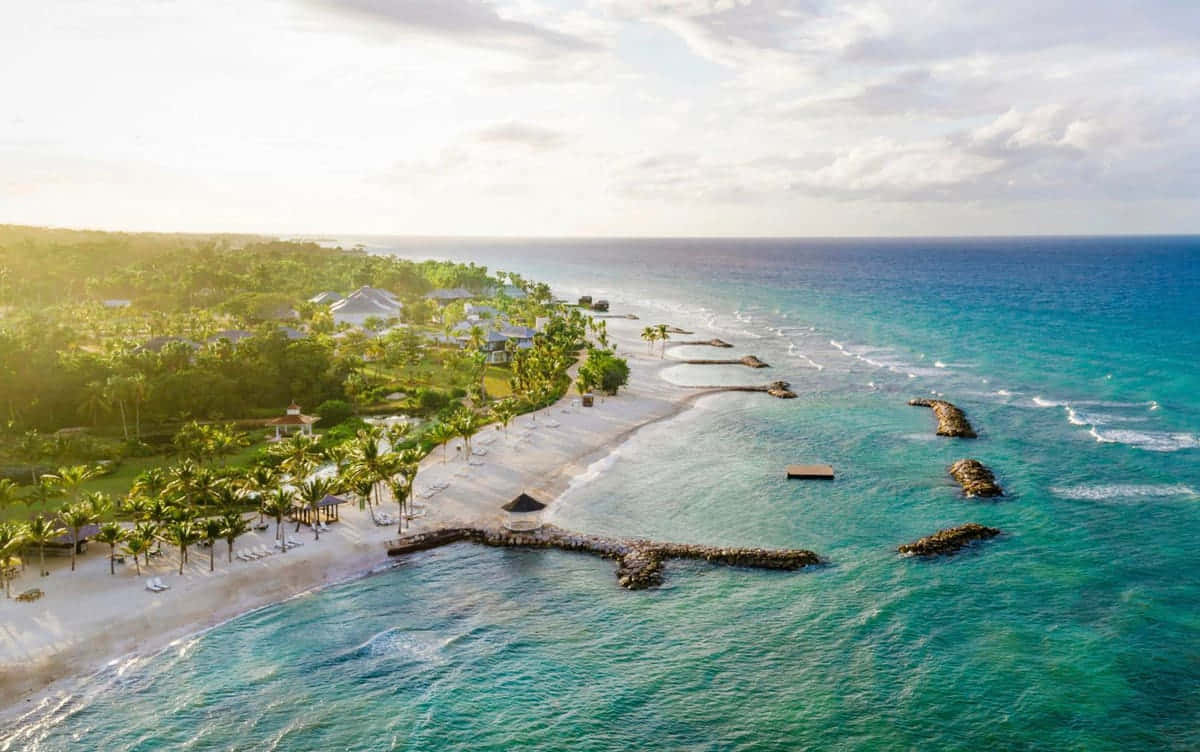 Jamaican Beach 桌布 壁紙 — 晴朗天空下，熱帶海灘度假村的鳥瞰圖，擁有碧綠海水、棕櫚樹和白色沙灘。