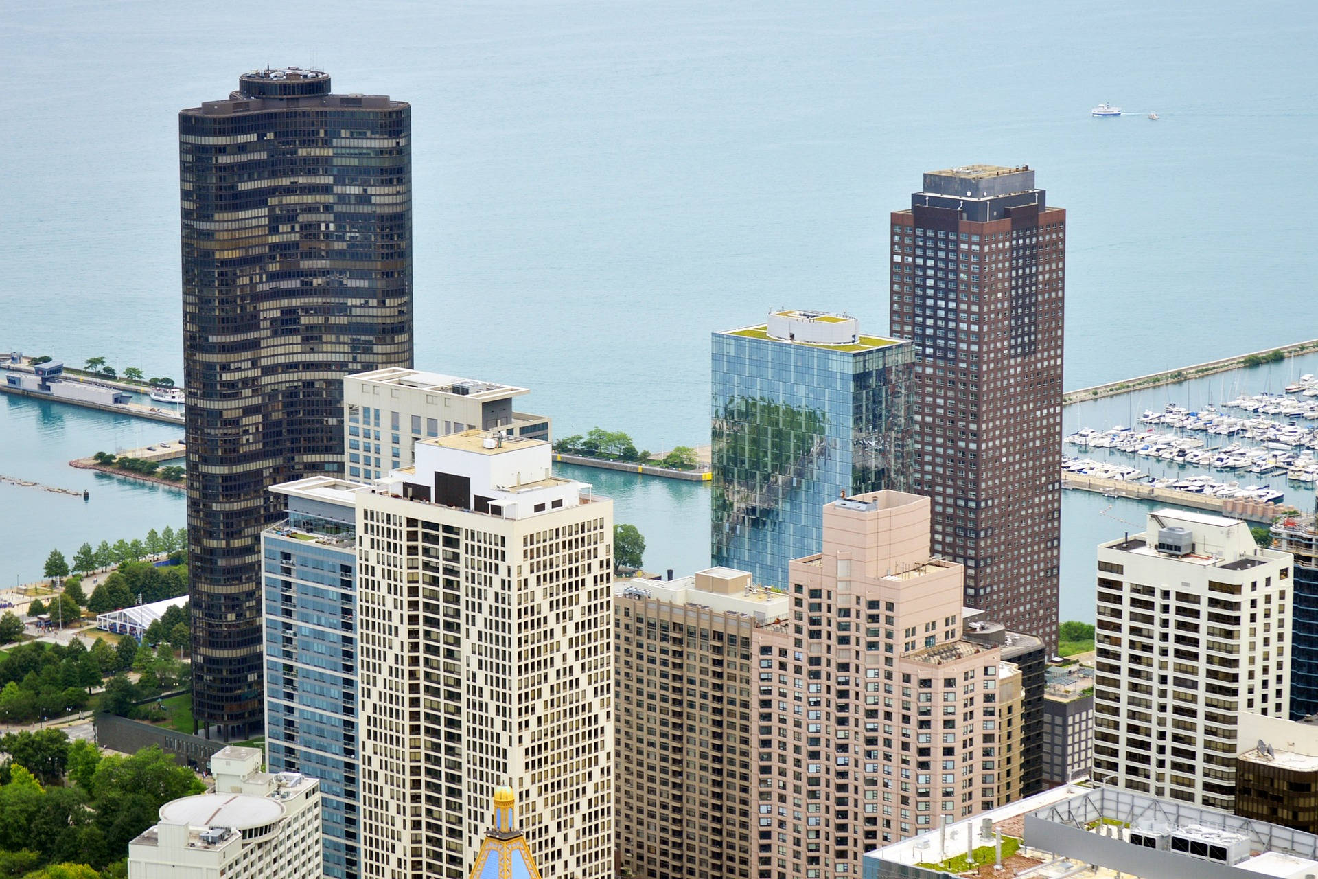 Skyscraper 桌布 壁紙 — 晴朗天空下，現代摩天大樓沿著海濱排列，碼頭船隻與平靜藍色海水的空拍視圖。