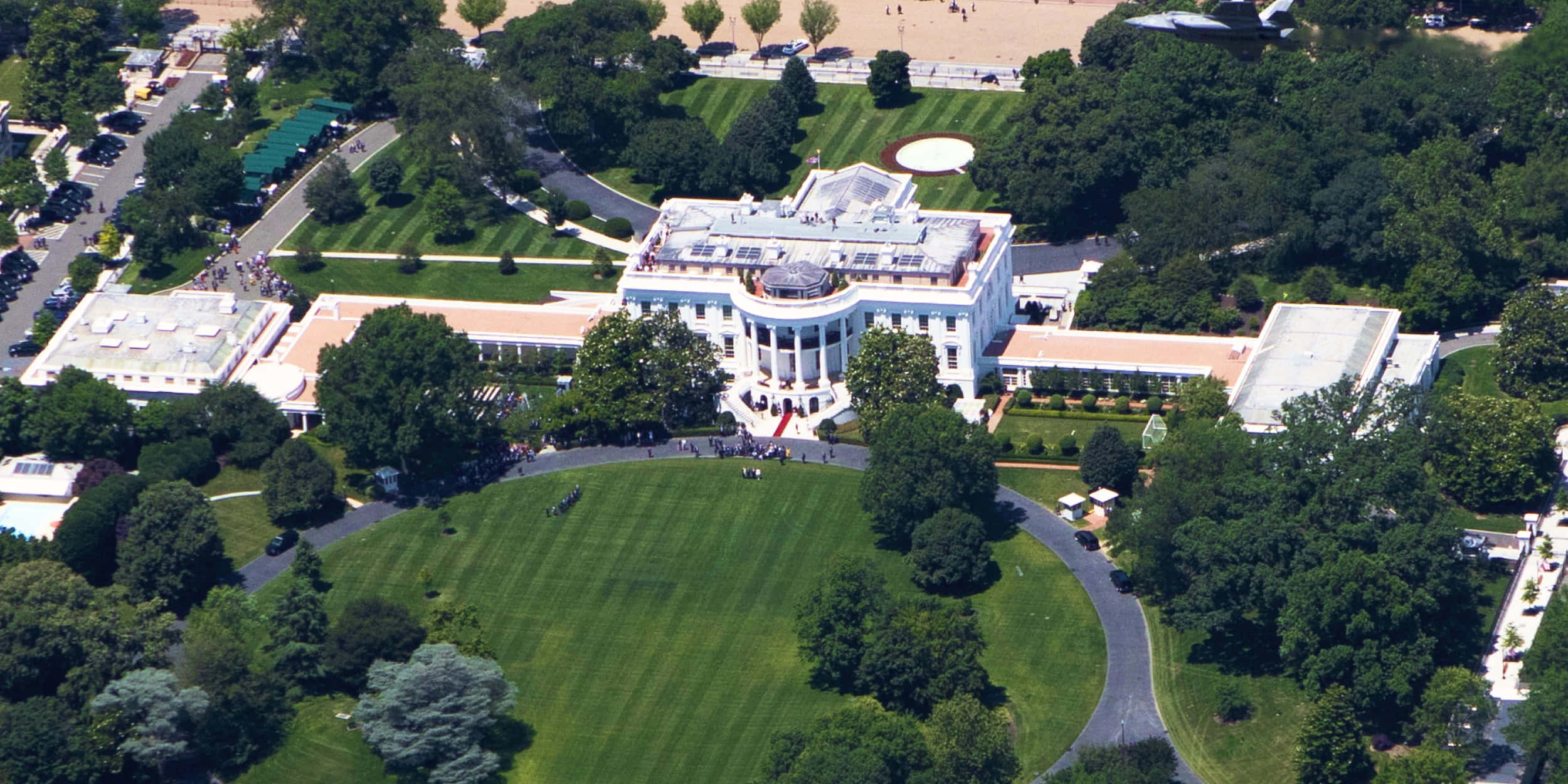 white house 桌布 壁紙 — 晴朗日子裡，白宮被茂密翠綠的草坪和樹木環繞的鳥瞰圖。