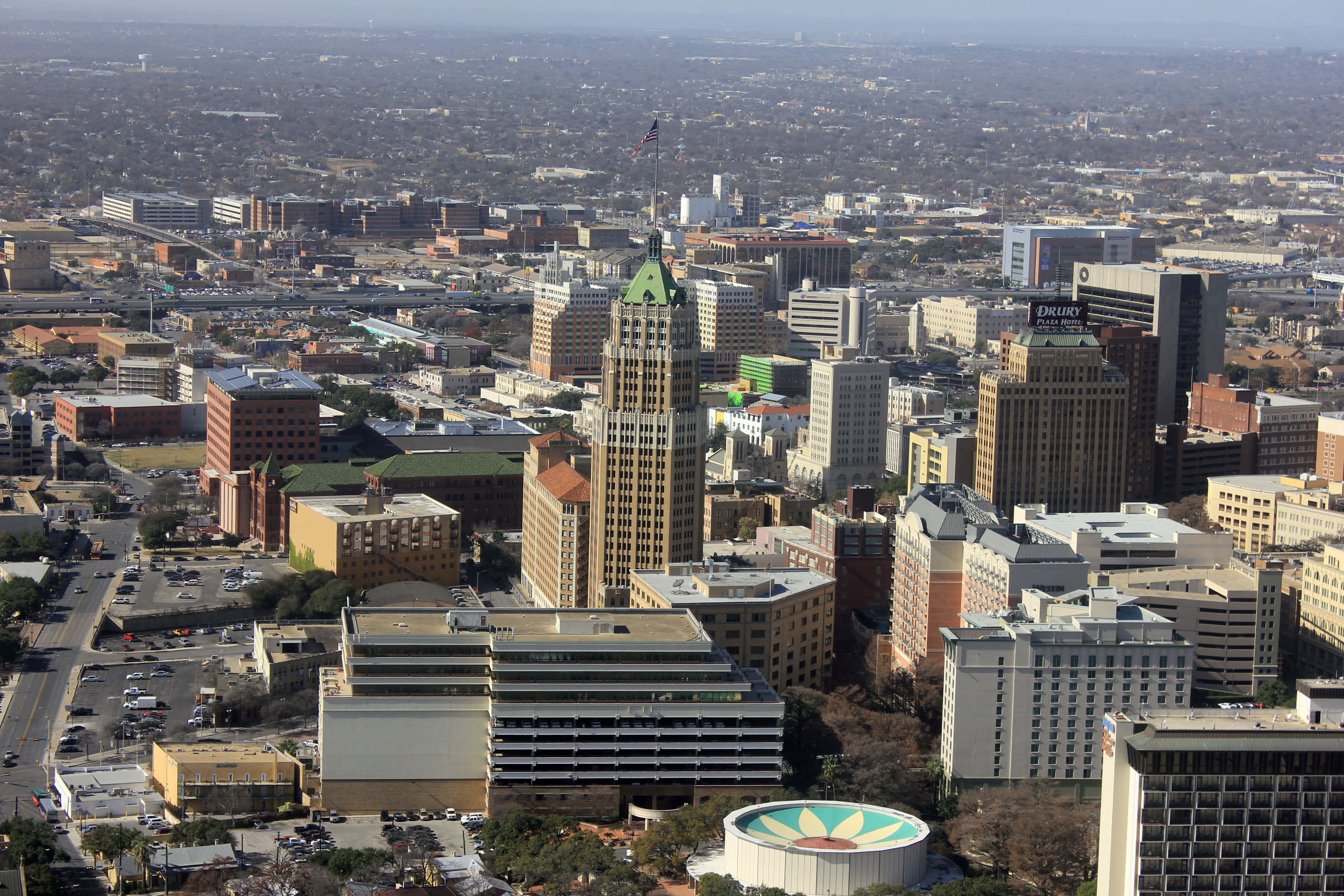 San Antonio 桌布 壁紙 — 晴朗日間下，高樓大廈與寬闊街道延伸的廣闊城市景觀鳥瞰圖。