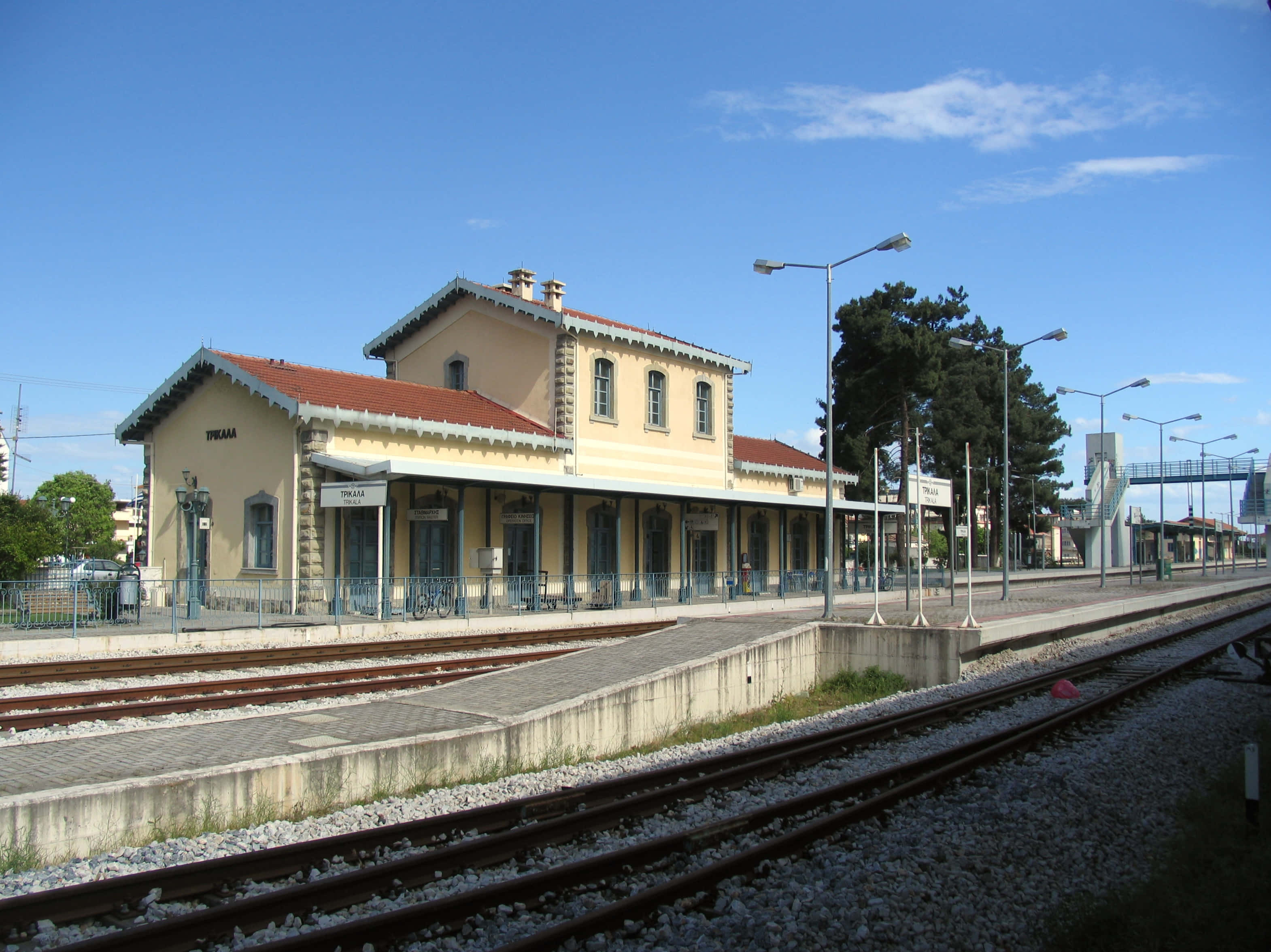 Train Station 桌布 壁紙 — 晴朗的一天，一個古雅的黃色火車站，紅色屋頂，多條軌道，在清澈的藍天下。