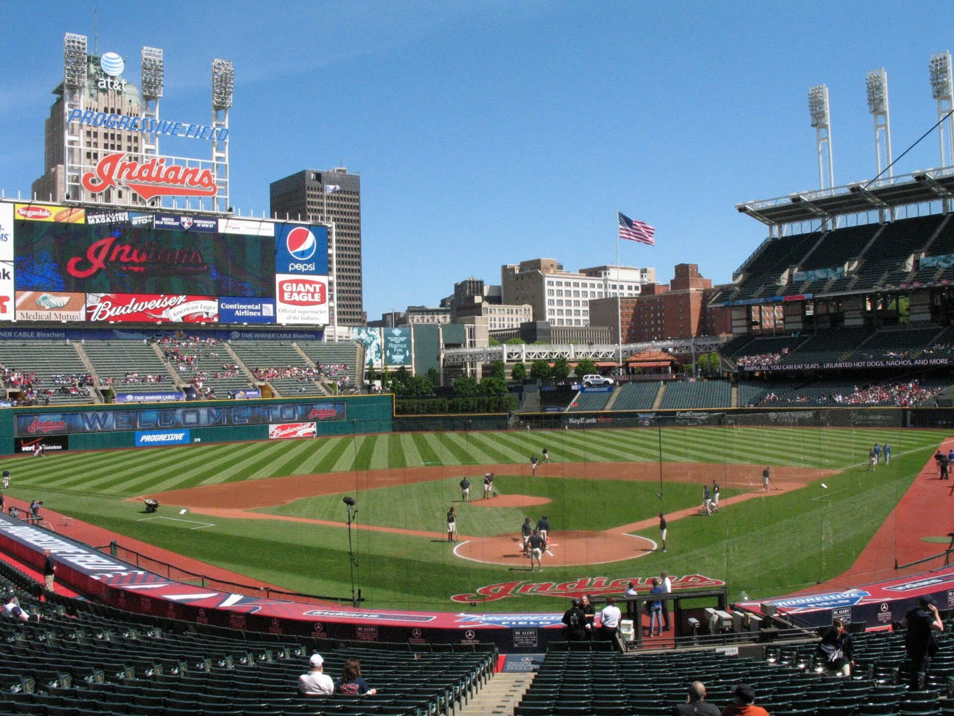 Cleveland Indians 桌布 壁紙 — 晴朗的一天，在棒球場上，球員們在場地上熱身，觀眾席上的球迷在清澈的藍天下。