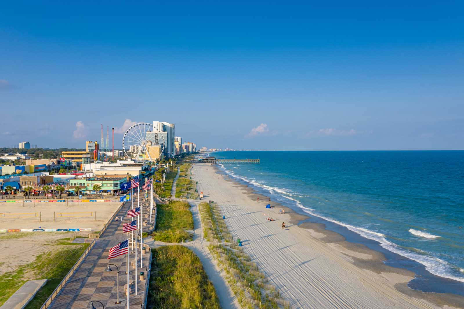 Myrtle Beach 桌布 壁紙 — 晴朗藍天下，充滿活力的海濱景觀，設有摩天輪遊樂園、沙灘和海洋波浪的鳥瞰圖。
