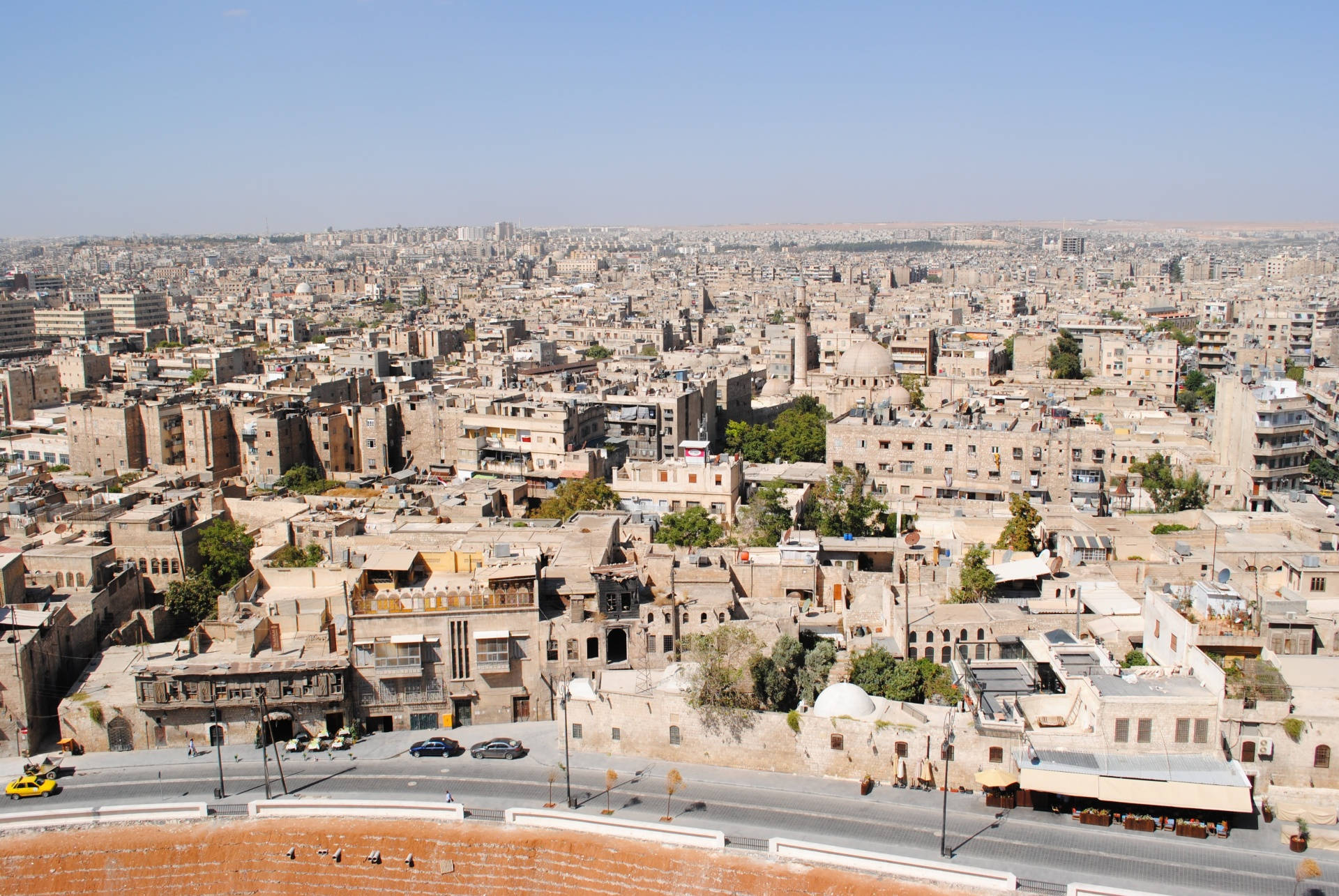 Syria 桌布 壁紙 — 晴朗藍天下，密集米色建築物延伸的廣闊城市景觀鳥瞰圖。