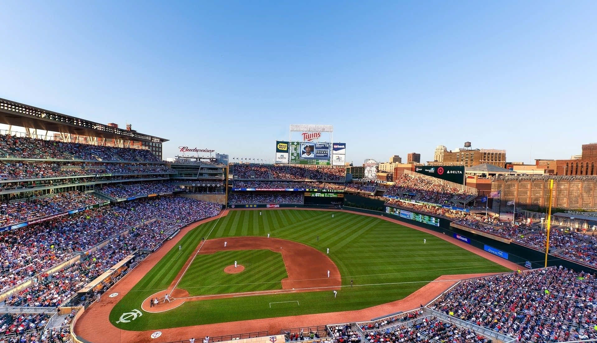 Baseball Stadium 桌布 壁紙 — 晴朗藍天下，滿座的棒球場空拍圖，場上有球員，球迷正在歡呼。