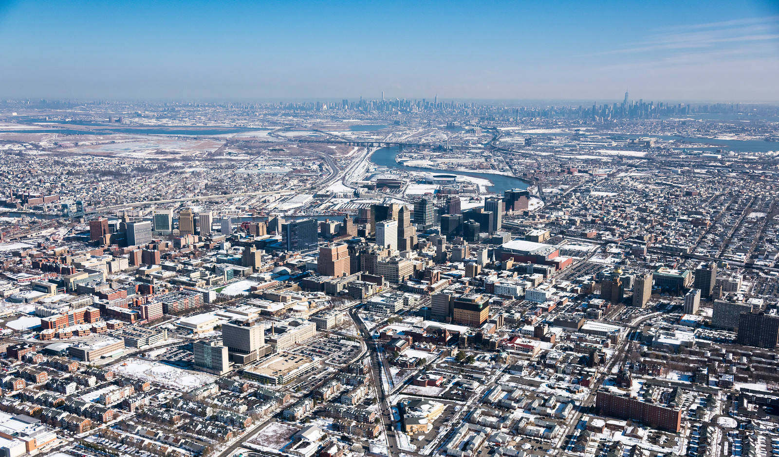 New Jersey 桌布 壁紙 — 晴朗藍天下，白雪覆蓋的城市擴展區，密集建築物與冰封水道的鳥瞰圖。