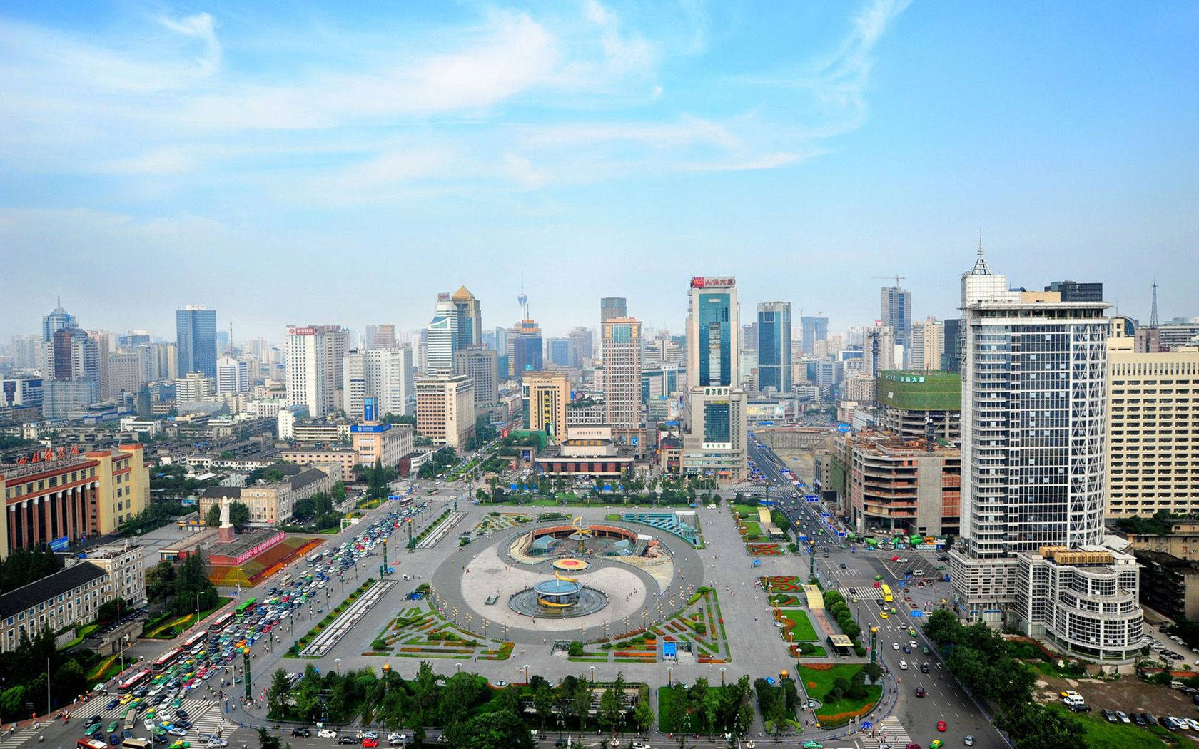 Chengdu 桌布 壁紙 — 晴朗藍天下，繁忙的現代城市景觀鳥瞰圖，圓形廣場周圍環繞著高聳的摩天大樓和繁忙的道路。