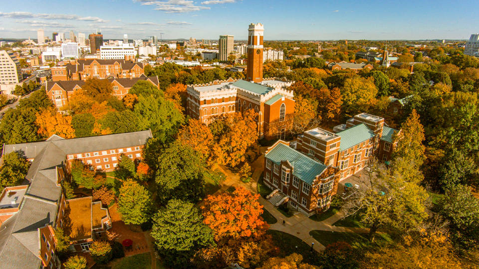 Vanderbilt University 桌布 壁紙 — 晴朗藍天下，被橙色和綠色秋葉環繞的歷史磚砌大學校園的鳥瞰圖。