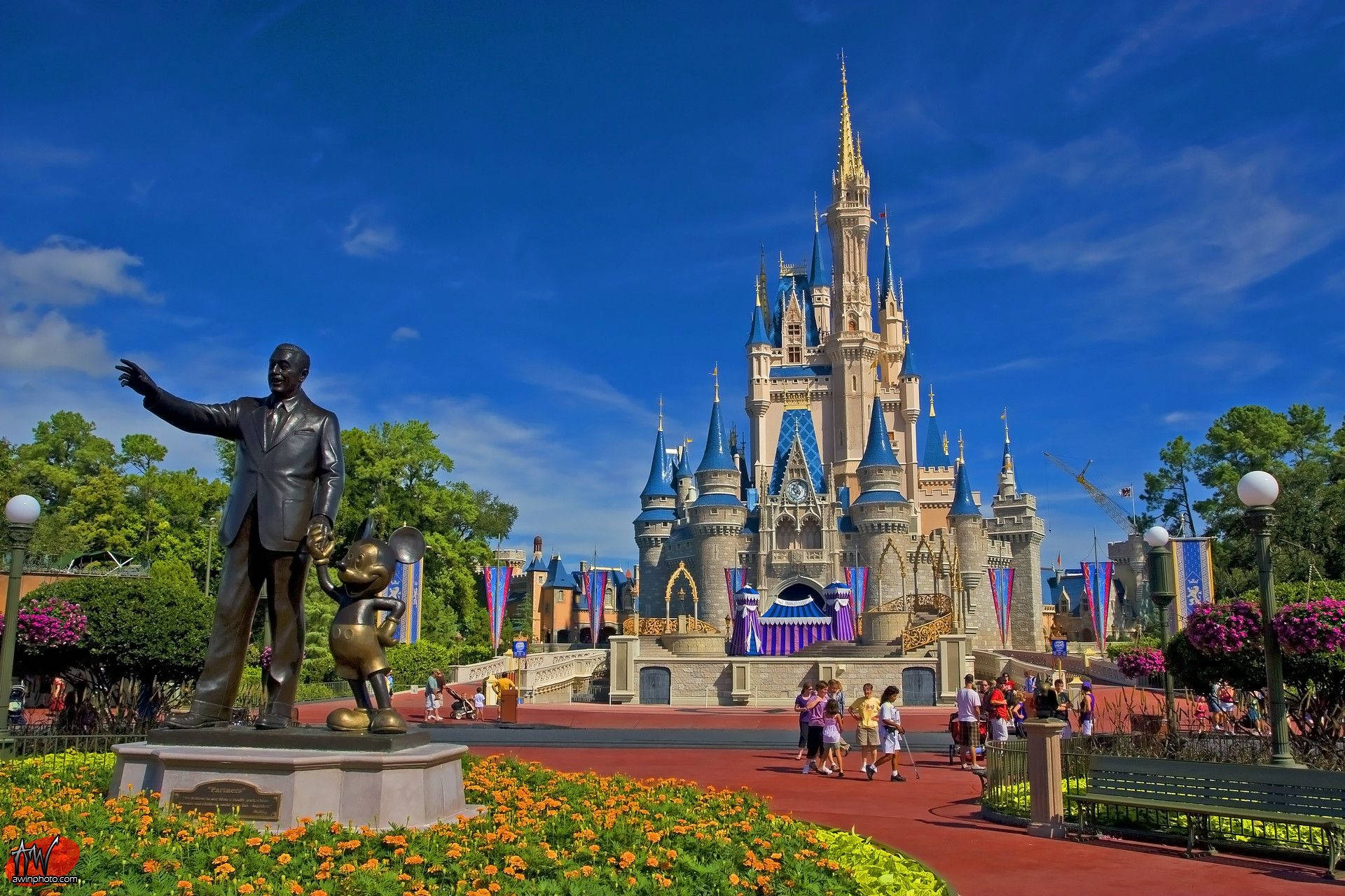 Disneyland Castle 桌布 壁紙 — 晴朗藍天下充滿活力的迪士尼城堡，前景有華特迪士尼和米奇老鼠的雕像。