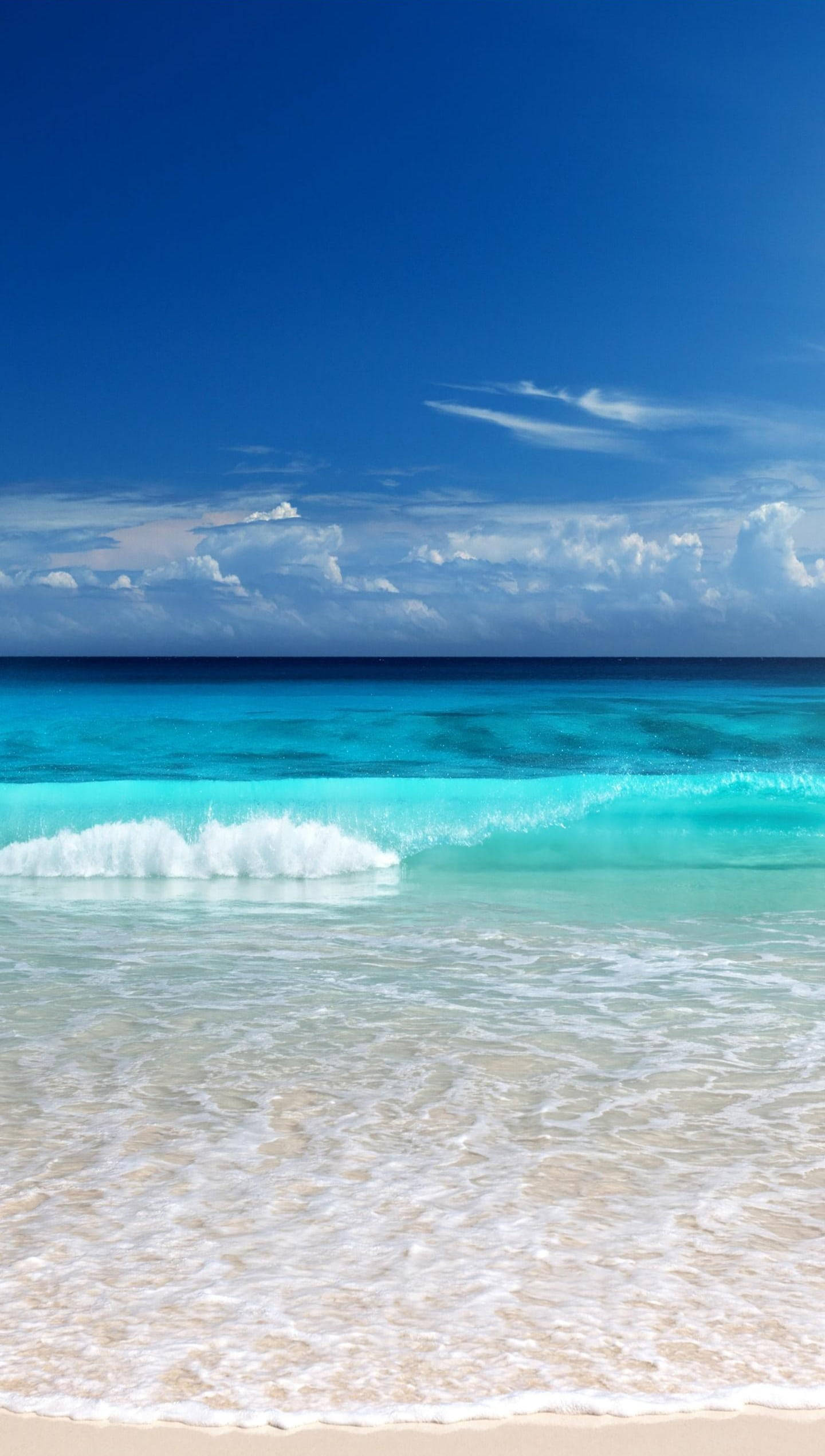 Beach Scene 桌布 壁紙 — 晶瑩剔透的碧綠海浪拍打著純淨的白色沙灘，上方是廣闊的藍天，點綴著幾朵白雲。