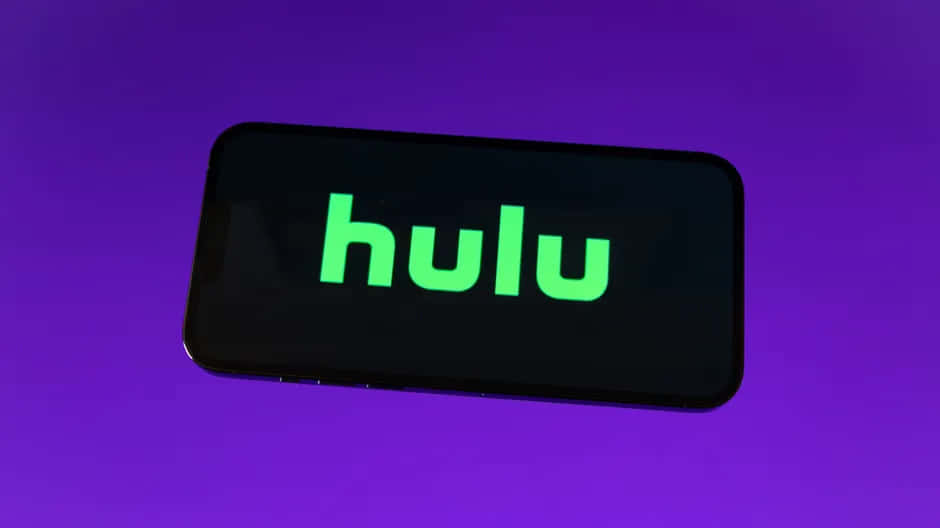 Hulu 桌布 壁紙 — 智慧型手機在充滿活力的紫色背景上顯示發光的綠色Hulu標誌。