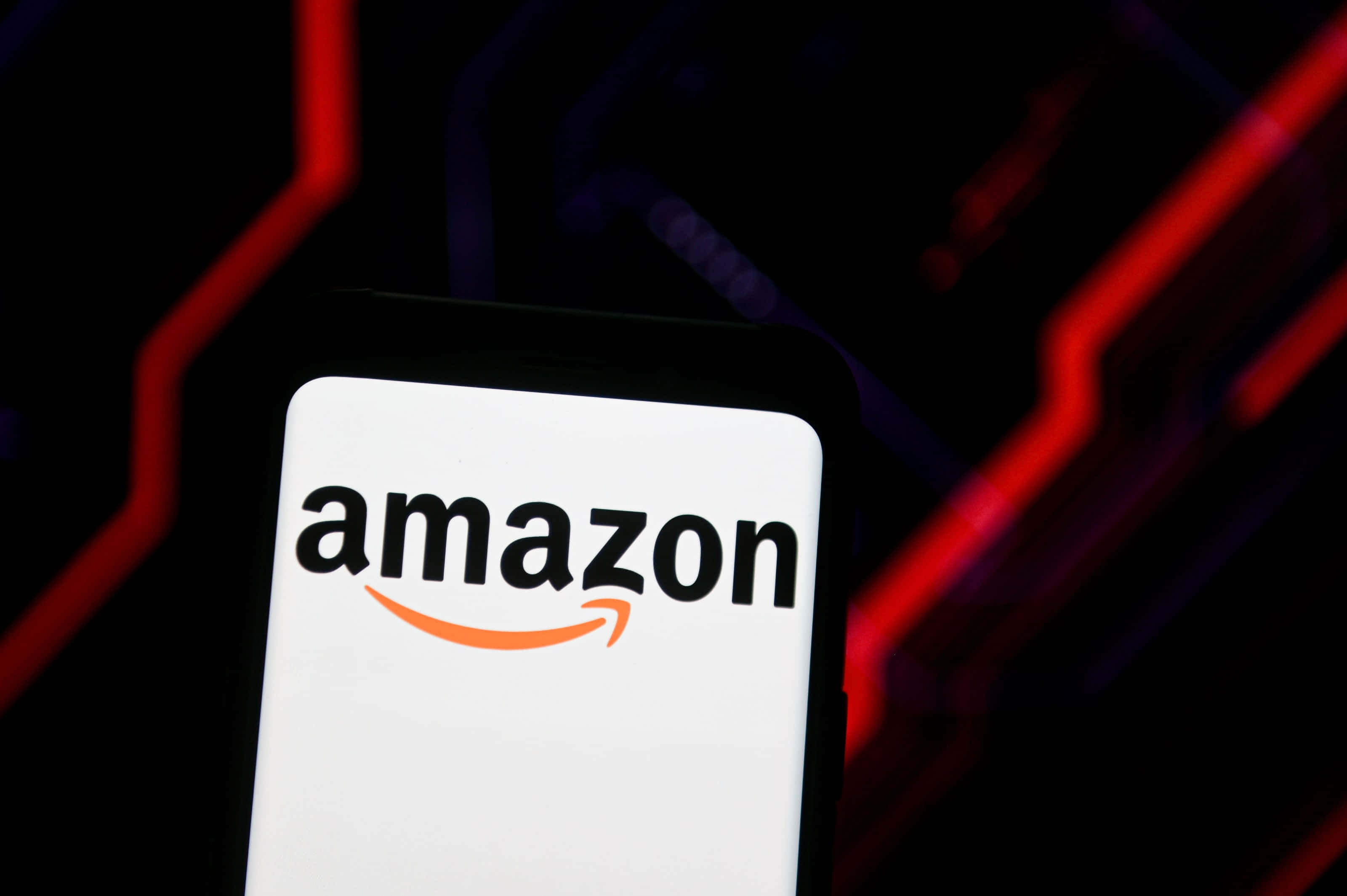 亞馬遜 桌布 壁紙 — 智慧型手機在深色背景上顯示Amazon標誌，並帶有發光的紅色霓虹線條。