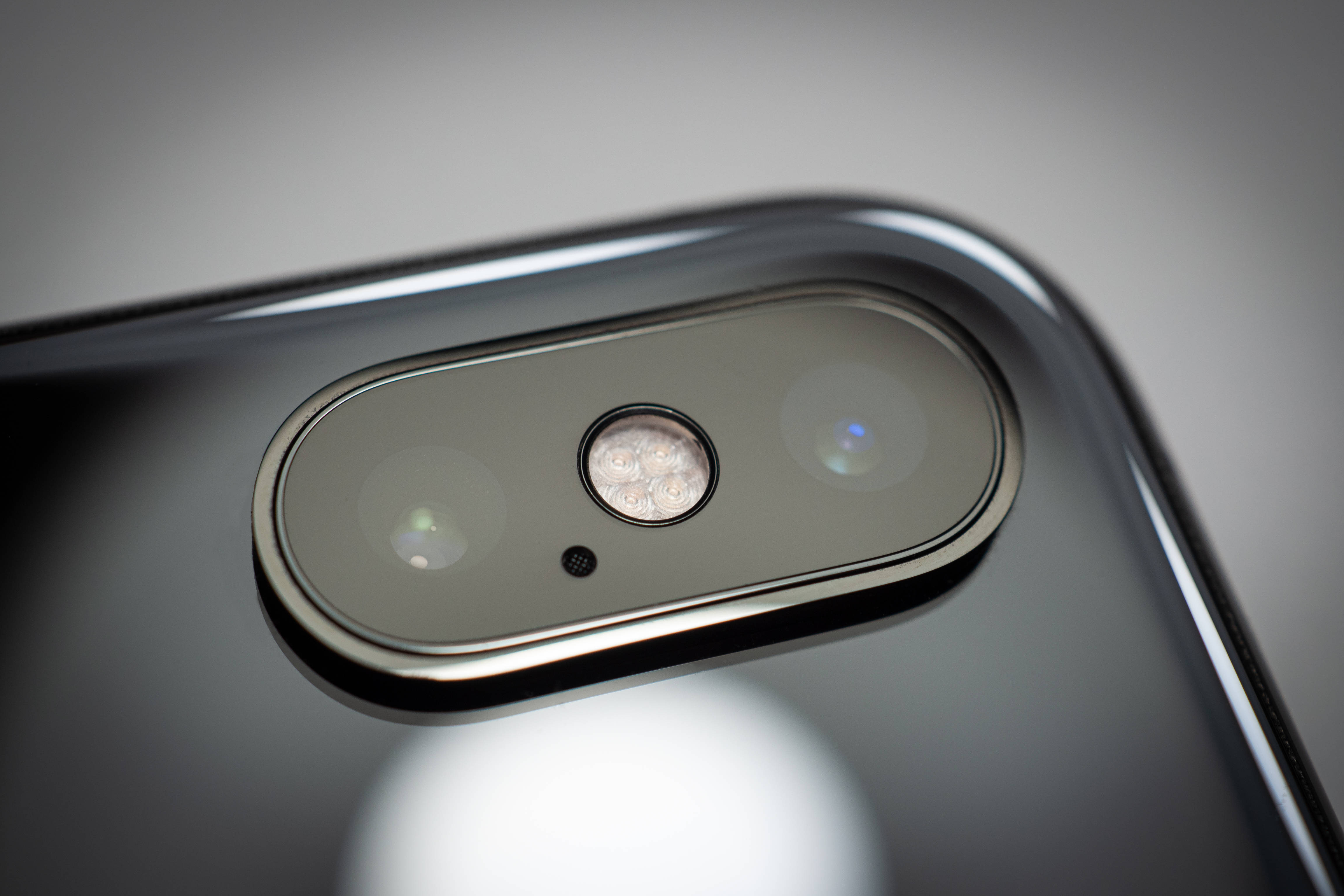 iPhone Xs Max 桌布 壁紙 — 智慧型手機相機模組特寫，配備雙鏡頭和閃光燈，背景為柔和灰色漸變。