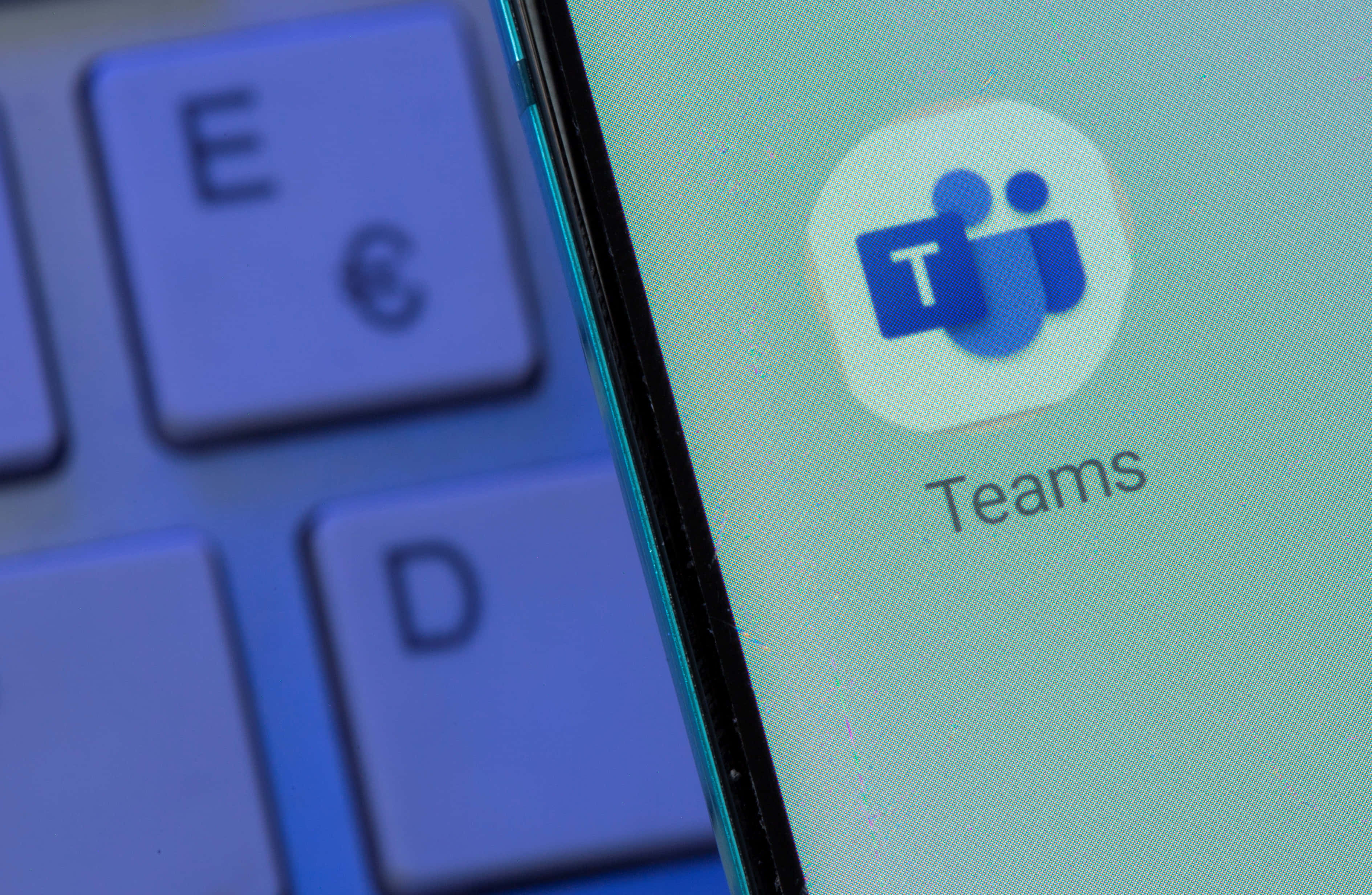 Microsoft Teams 桌布 壁紙 — 智慧型手機螢幕上Microsoft Teams應用程式圖示的特寫，旁邊是模糊的鍵盤。