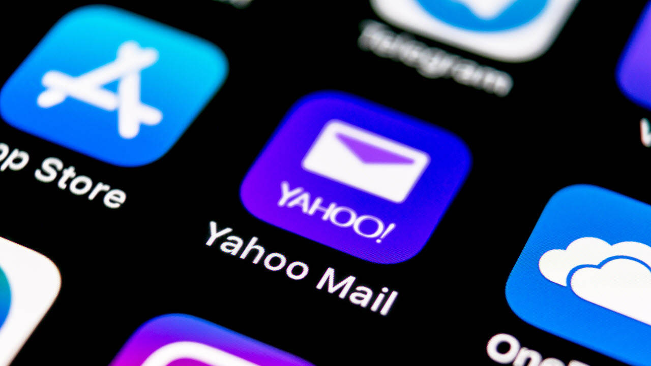 Yahoo Mail 桌布 壁紙 — 智慧型手機螢幕特寫，顯示Yahoo Mail應用程式圖示在深色背景上與其他應用程式圖示一起發出紫色光芒。