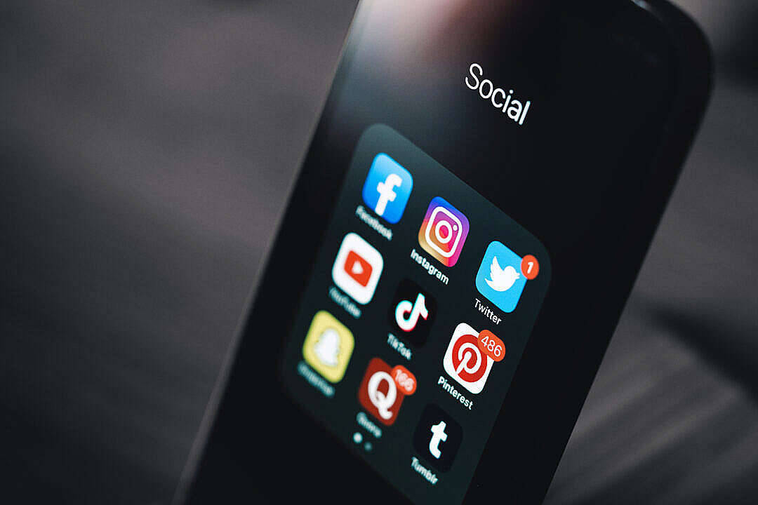 simple dark aesthetic 桌布 壁紙 — 智慧型手機螢幕特寫，顯示一個「社交」資料夾，內有 Instagram、Twitter 和 TikTok 等應用程式圖標，背景為模糊的深色。
