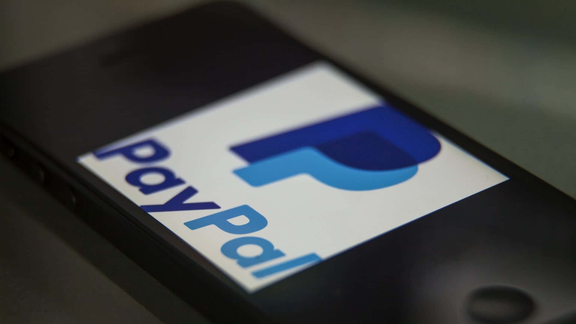 PayPal 桌布 壁紙 — 智慧型手機螢幕特寫，顯示藍色和白色的PayPal標誌，背景模糊深色。