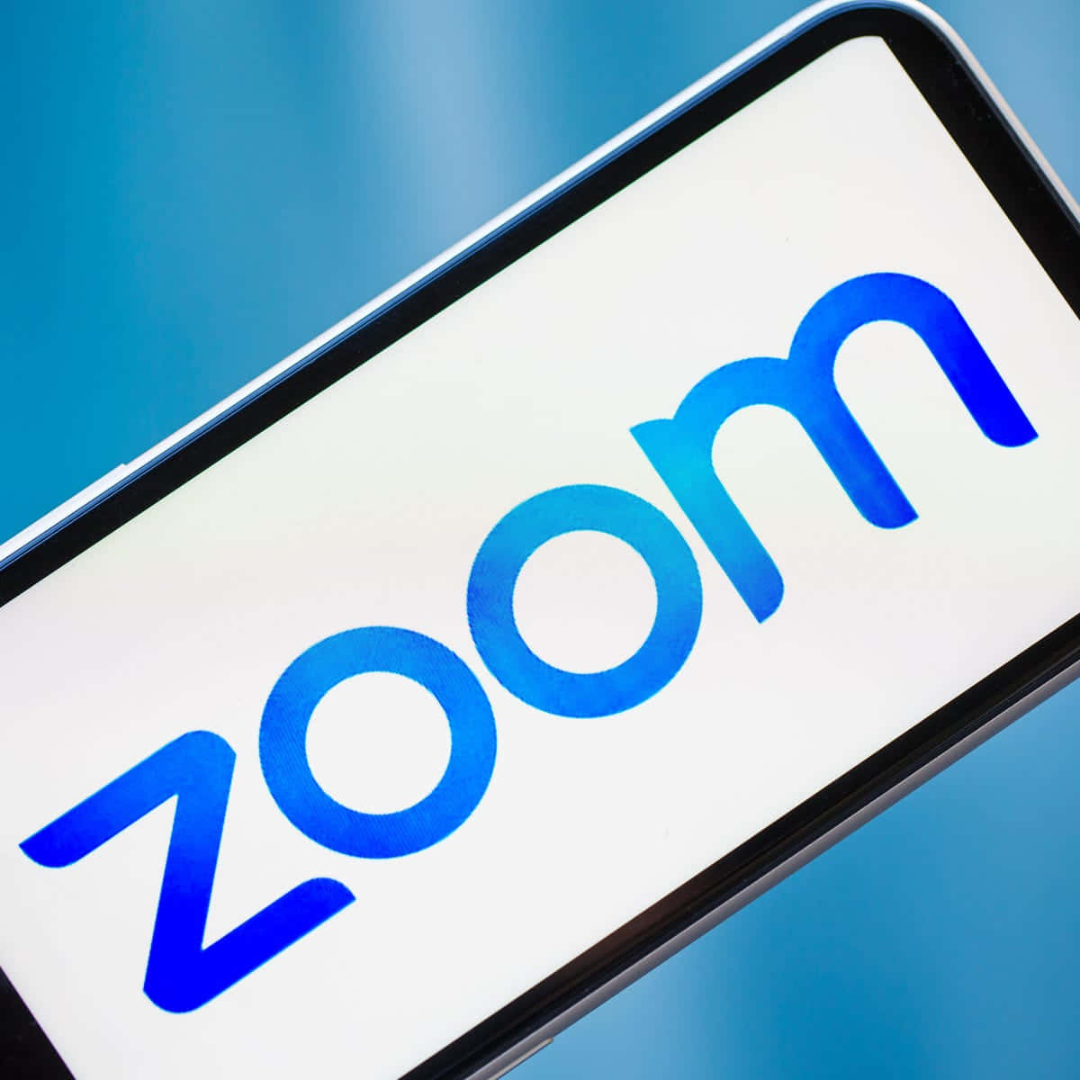 智慧型手機在藍色背景上顯示 Zoom 應用程式標誌。 — 放大 壁紙