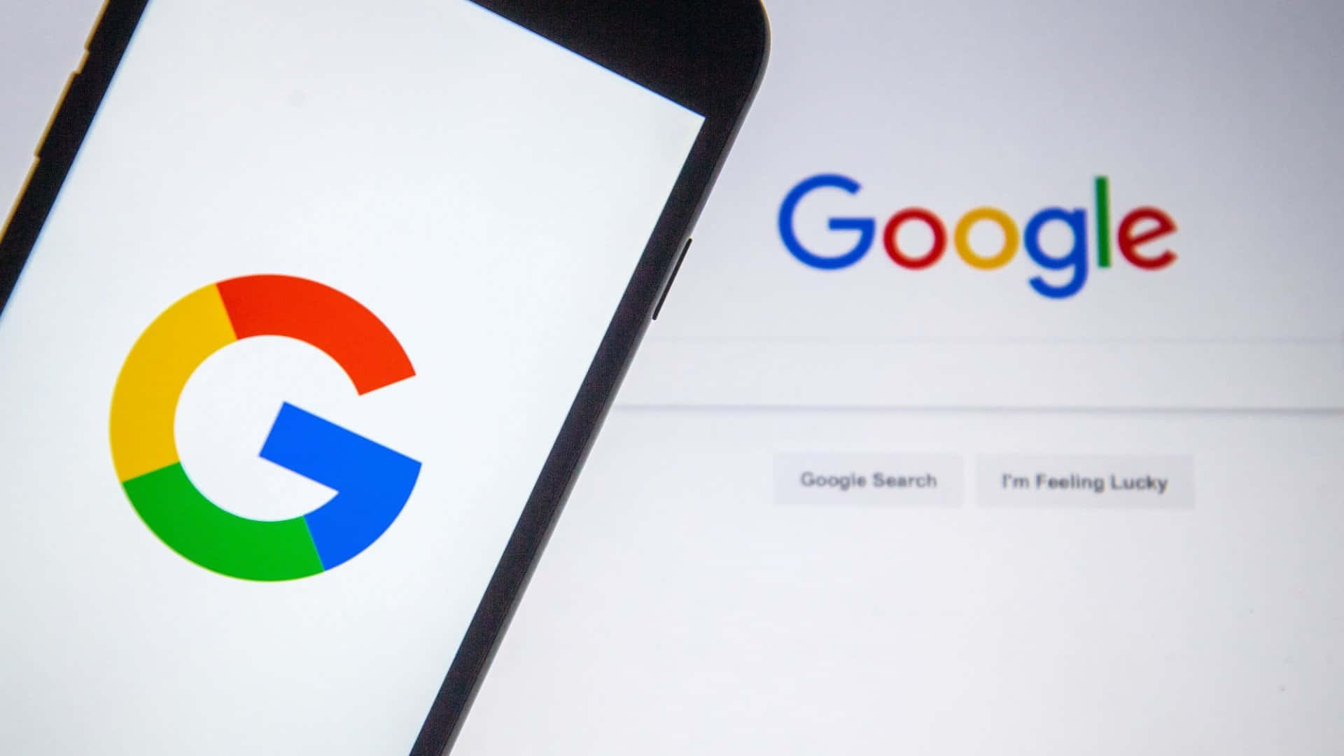 google 桌布 壁紙 — 智慧型手機顯示Google標誌，同時電腦螢幕顯示經典的Google首頁及搜尋按鈕。