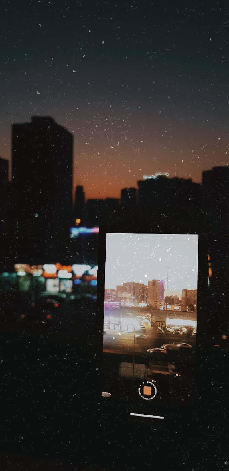 Night Time 桌布 壁紙 — 智慧型手機顯示黃昏時分的城市景觀，背後雪花飄落，襯托著繁星點點的夜空。
