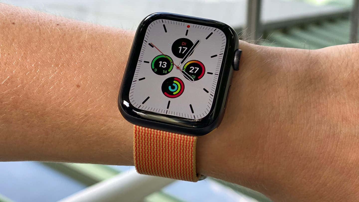 Apple Watch 動態 桌布 壁紙 — 智慧手錶特寫，配戴橙色編織錶帶於手腕上，顯示活動指標。