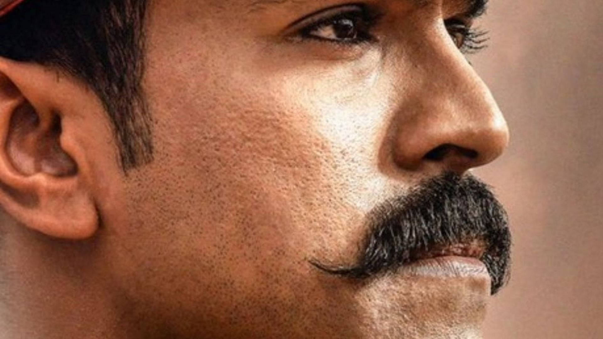 Indian 桌布 壁紙 — 暖色燈光下，一位留著濃密鬍鬚的男子若有所思地側視的特寫肖像。