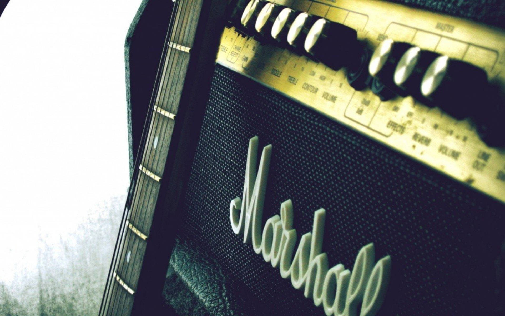 Marshall 桌布 壁紙 — 暖色燈光下，復古Marshall吉他音箱近距離特寫，吉他頸靠在其上。
