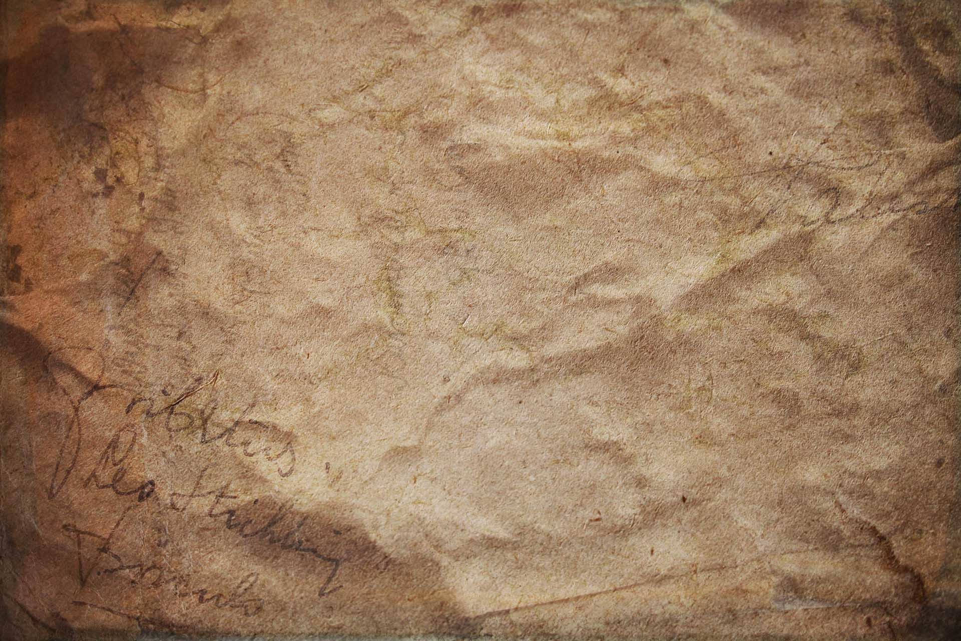 old 桌布 壁紙 — 暖色燈光下，老化羊皮紙的特寫，帶有褪色的草書手寫字跡和可見的摺痕。