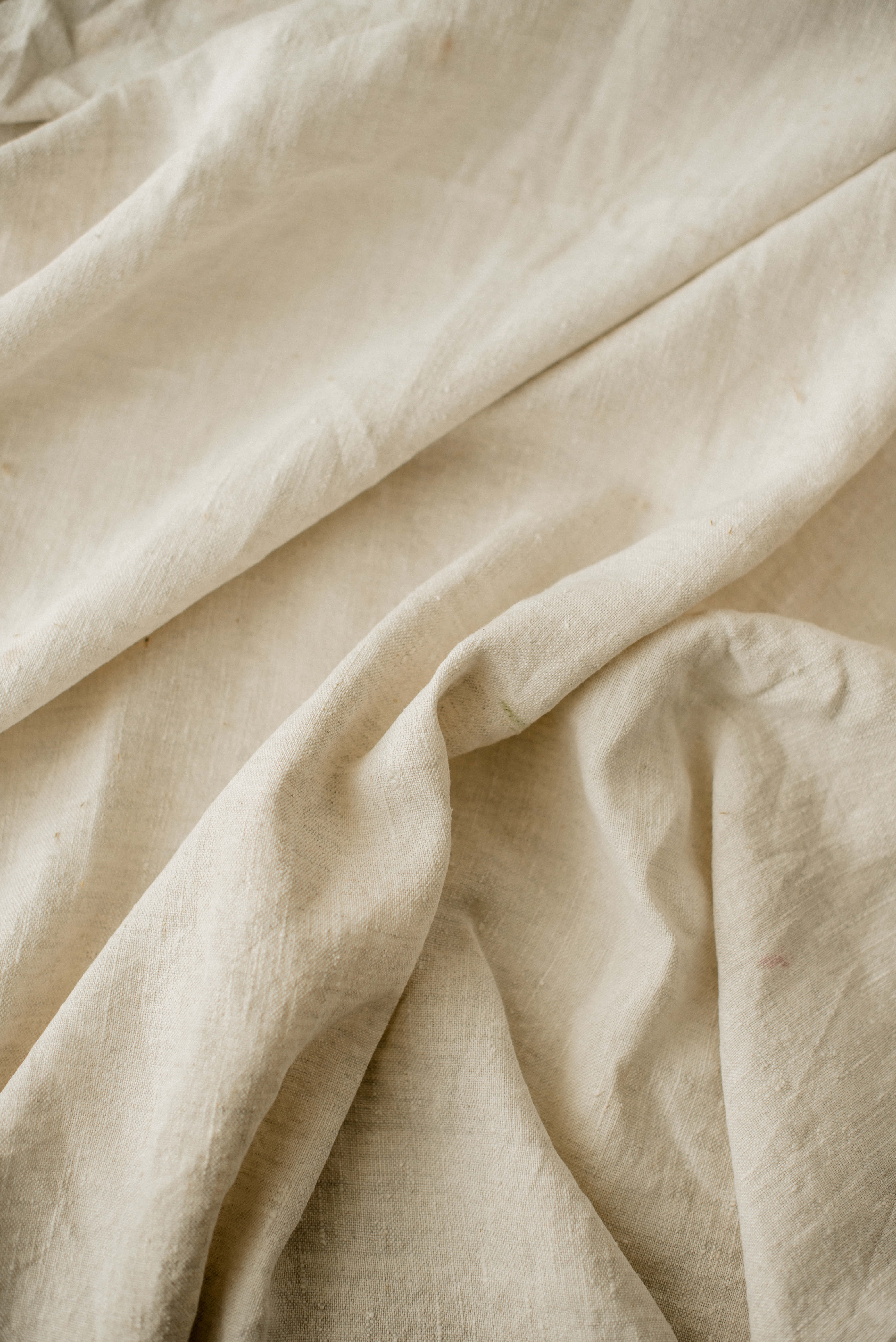 Linen 桌布 壁紙 — 暖色燈光下柔軟米色亞麻布料的特寫，帶有自然皺褶和細微紋理。