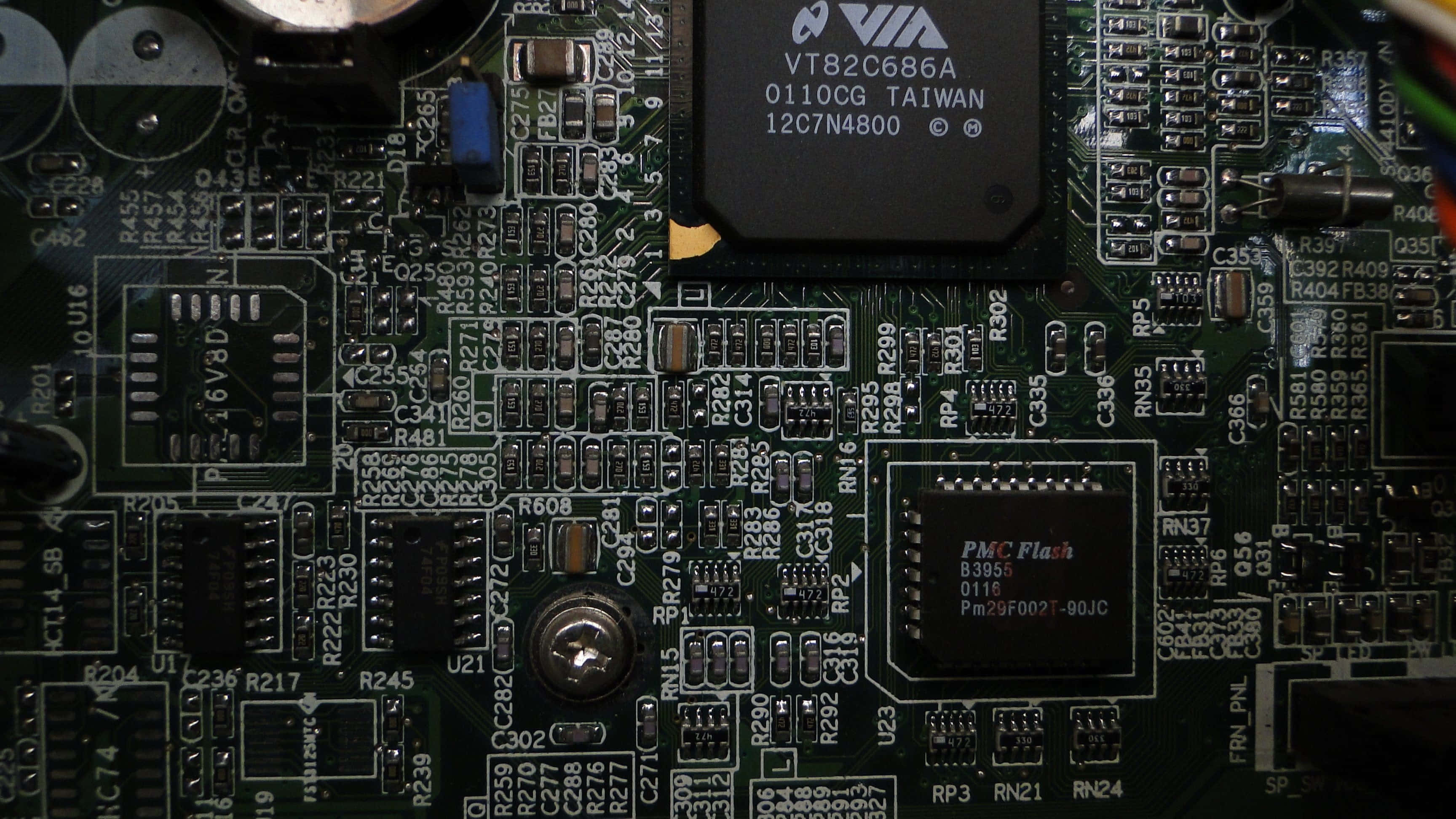 Electronic Components 桌布 壁紙 — 暖色燈光下綠色電路板的特寫，帶有標籤晶片、電阻器和焊接元件。
