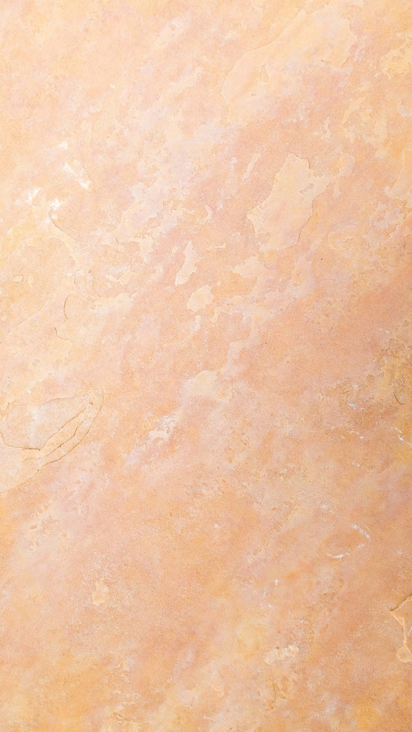 Aesthetic Rose Gold 桌布 壁紙 — 暖蜜桃色紋理牆壁的特寫，帶有微妙的顏色變化和表面瑕疵。
