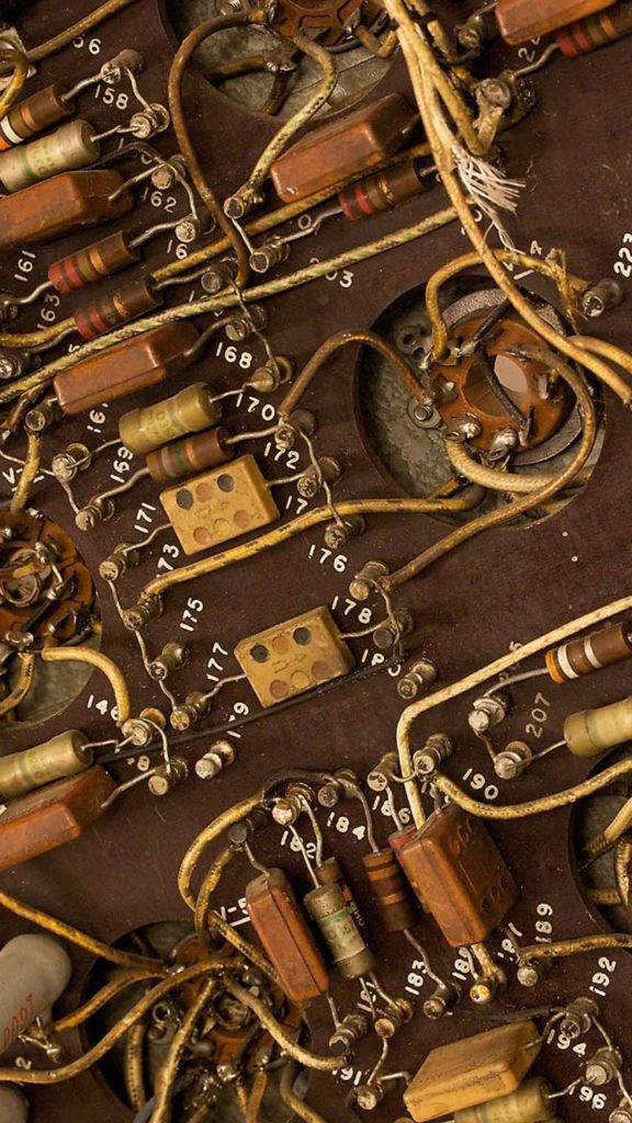 Brown iPhone 桌布 壁紙 — 暗棕色電路板上帶有纏繞電線和編號電阻的復古電子元件特寫。