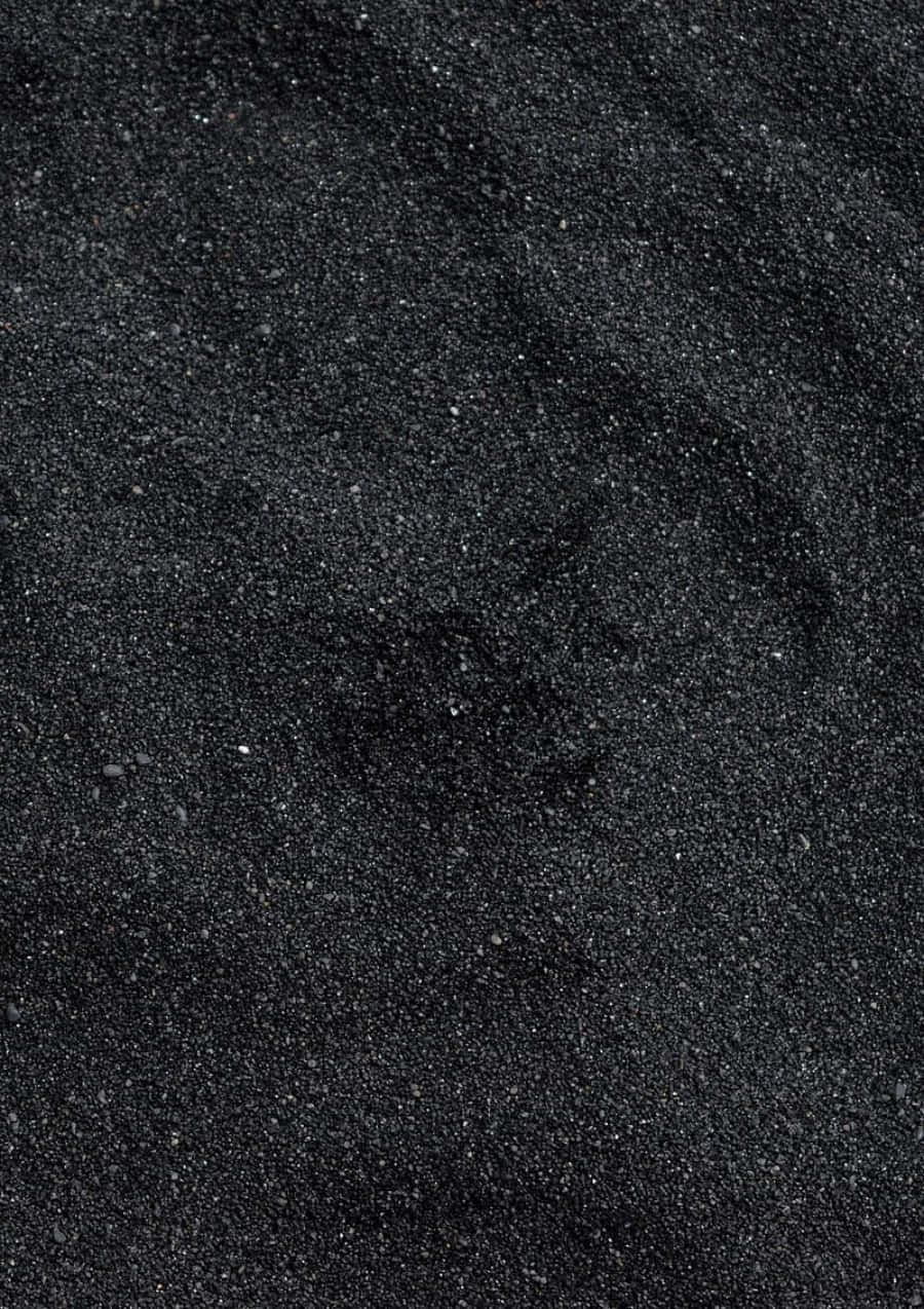 Black Powder 桌布 壁紙 — 暗色紋理沙粒的微距特寫，在柔和光線下帶有細微閃爍顆粒。