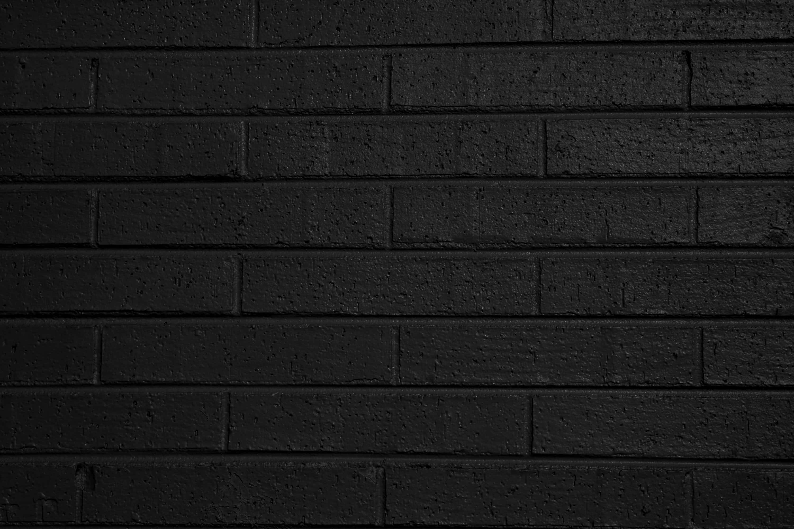 Brick 桌布 壁紙 — 暗色紋理磚牆的特寫，微妙的陰影突顯其粗糙表面。