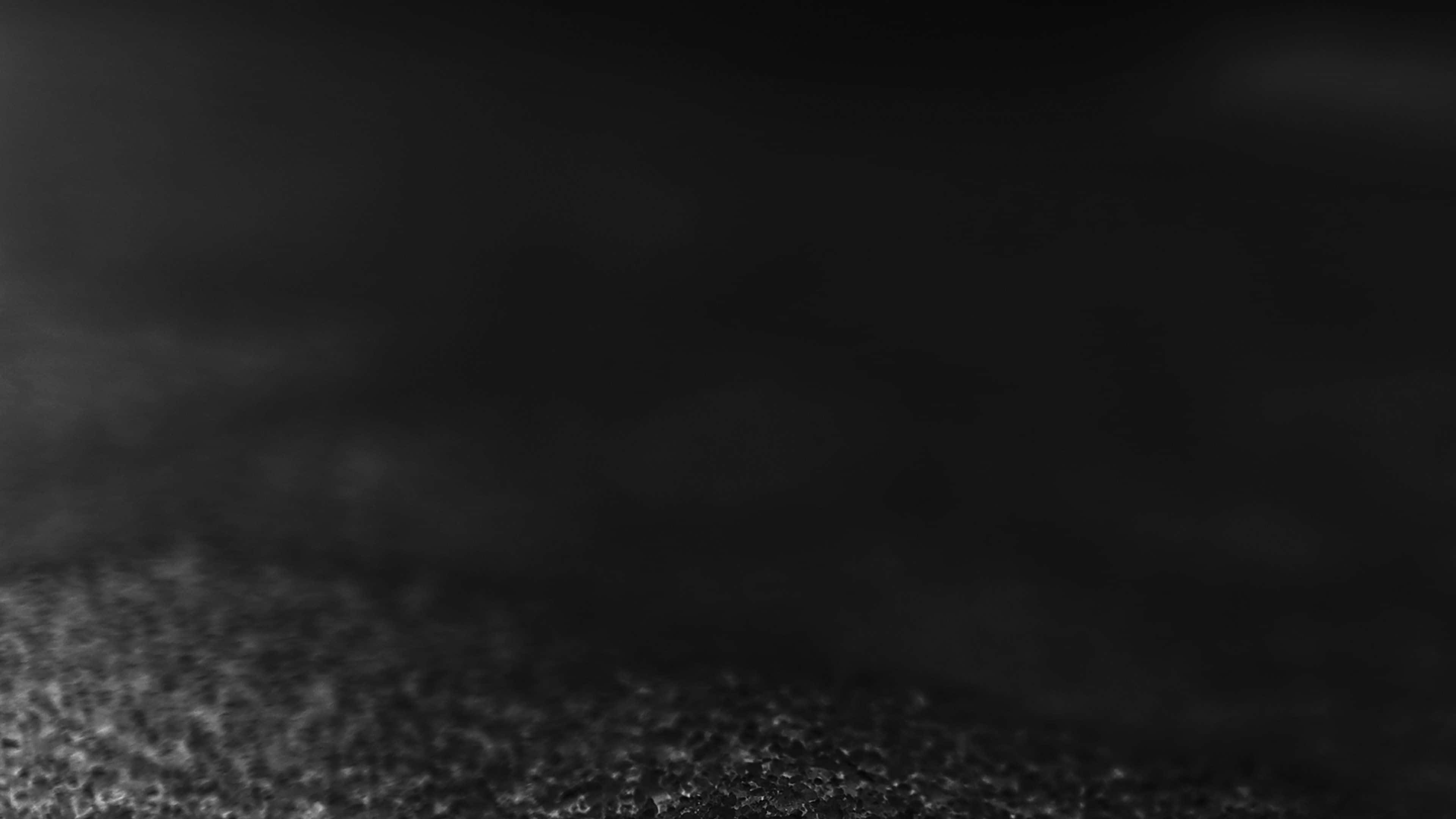 Dust Particles 桌布 壁紙 — 暗色紋理表面的特寫，帶有柔和漸變照明和微妙的散景效果。
