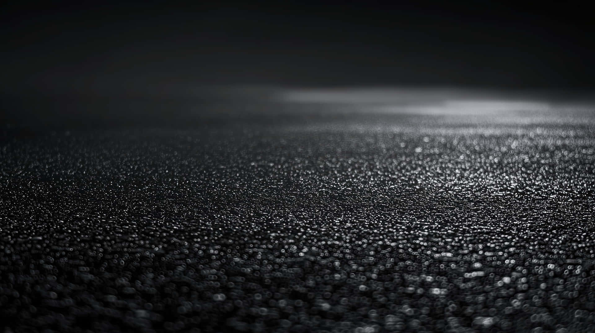 Wet Black Surface with Glowing Light Reflection in Darkness 壁紙 — 暗色紋理表面的特寫，有一條明亮的水平光條照亮前景。