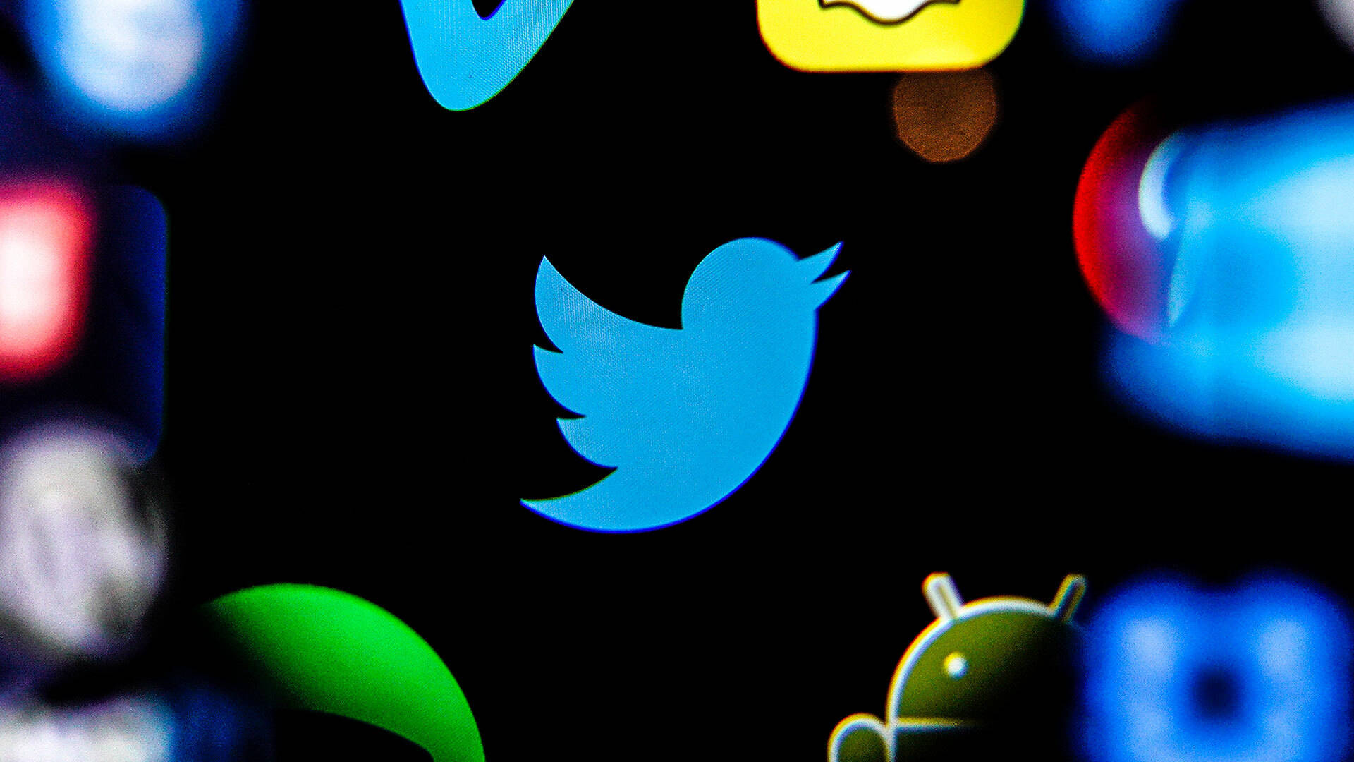 Twitter 桌布 壁紙 — 暗色螢幕上模糊應用程式圖標中，一個發光藍色Twitter鳥圖標的特寫。