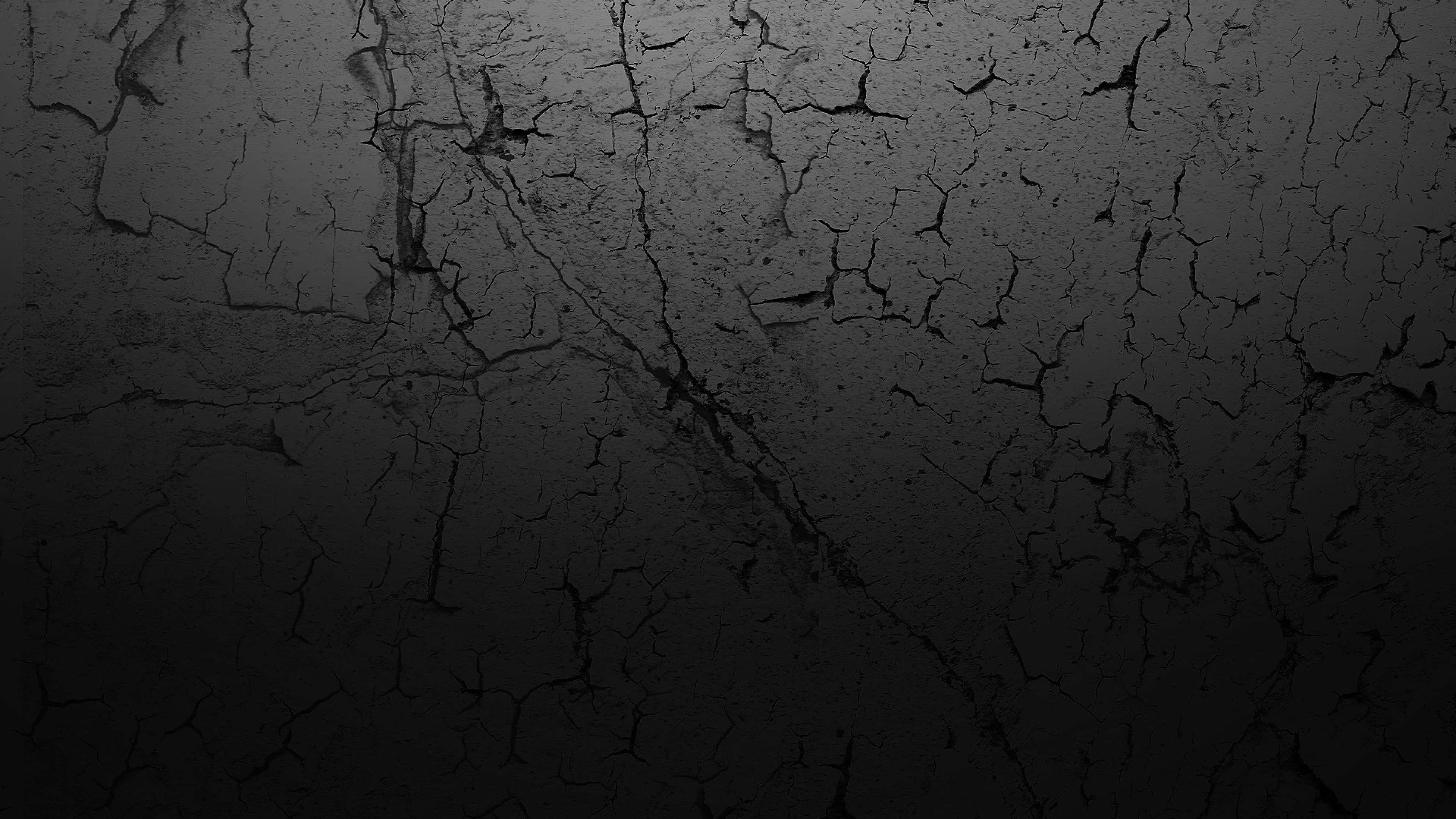 Dark Texture 桌布 壁紙 — 暗色裂紋混凝土表面的特寫，帶有微妙的漸變照明。