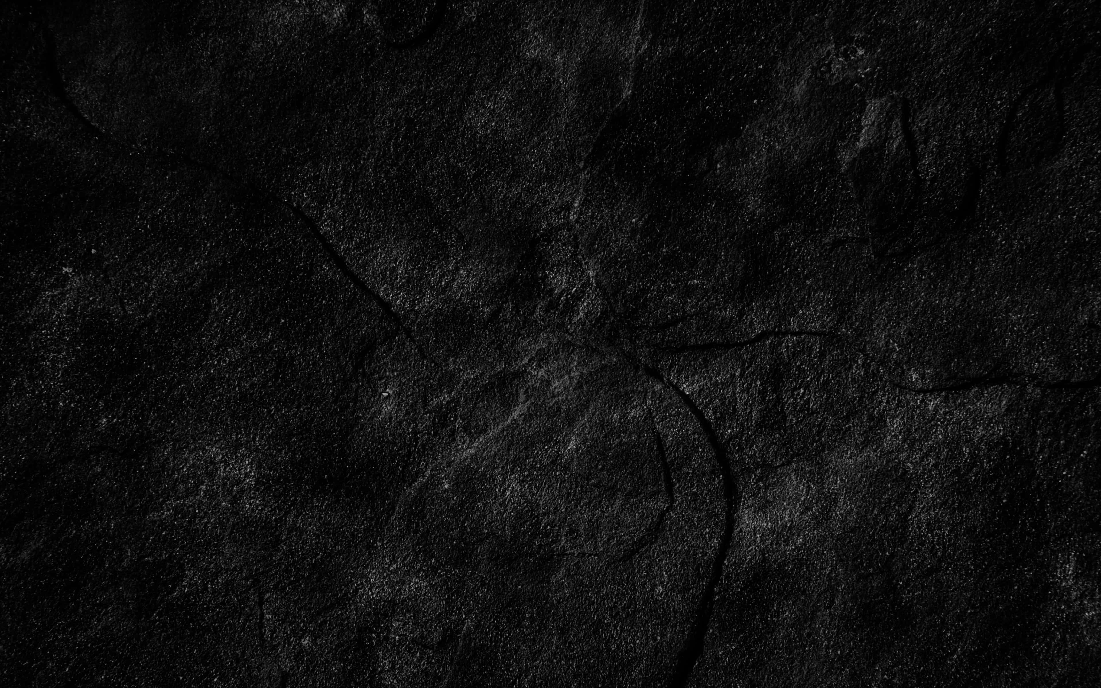 Dark Rock 桌布 壁紙 — 暗色裂紋混凝土表面的特寫，帶有細微紋理和淡淡的灰色高光。