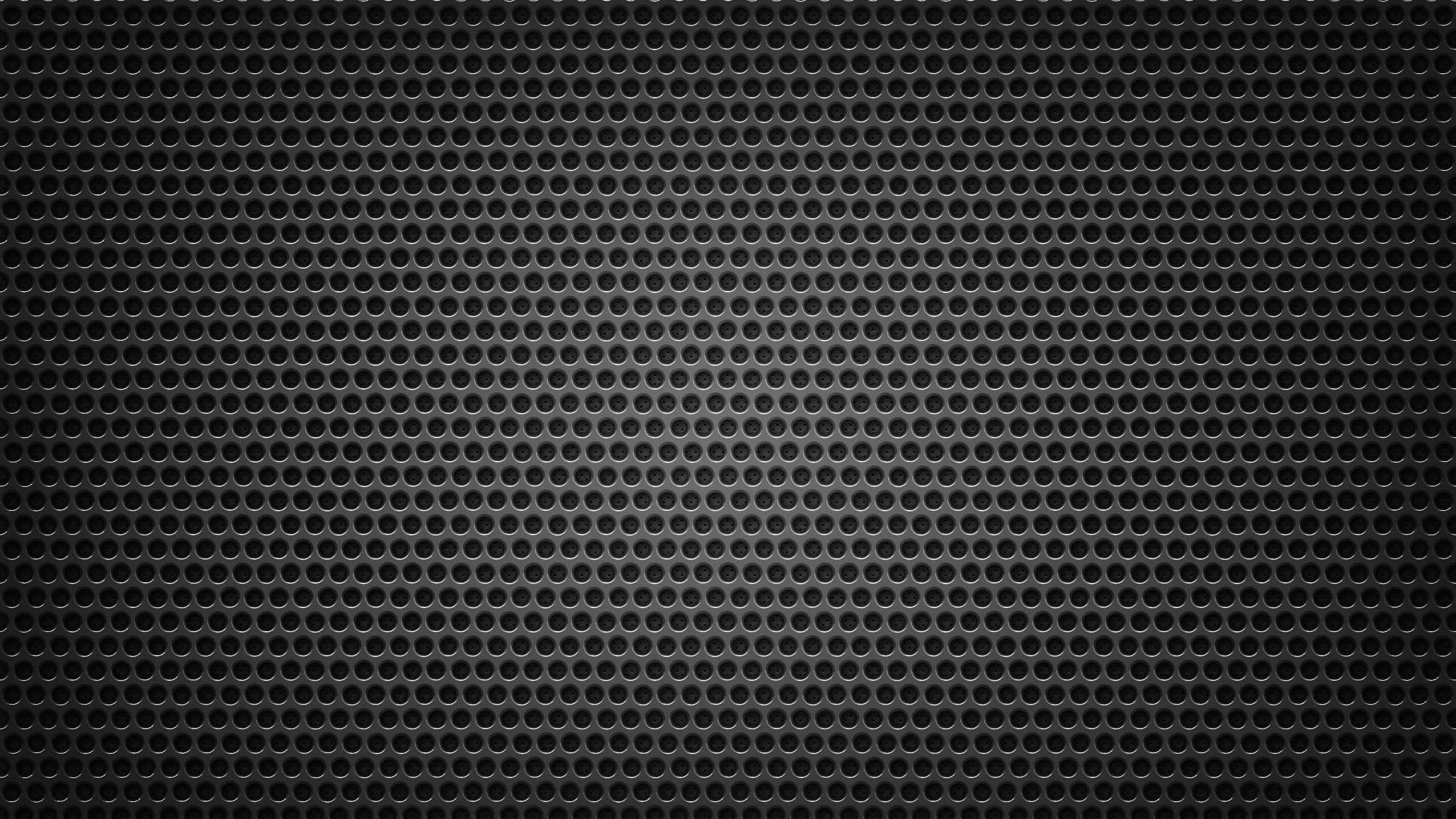Metal Texture 桌布 壁紙 — 暗色金屬穿孔表面的特寫，帶有微妙的漸變照明效果。